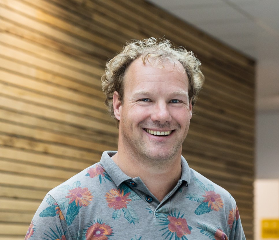 Medewerker van Noorderpoort lacht en straalt enthousiasme uit in een inspirerende leeromgeving
