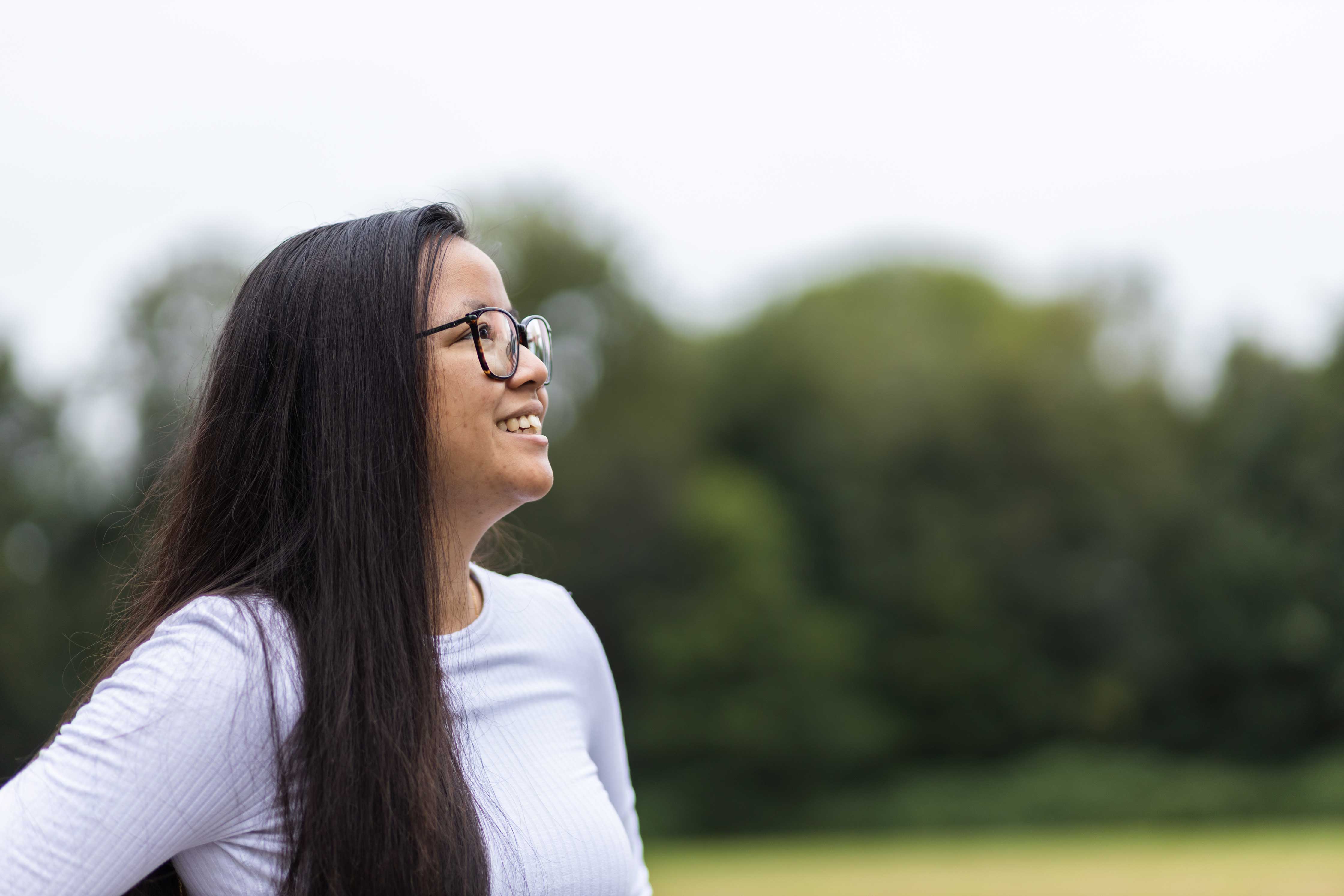 Een betrokken student met een passie voor ICT kijkt vooruit in een groene buitenruimte.