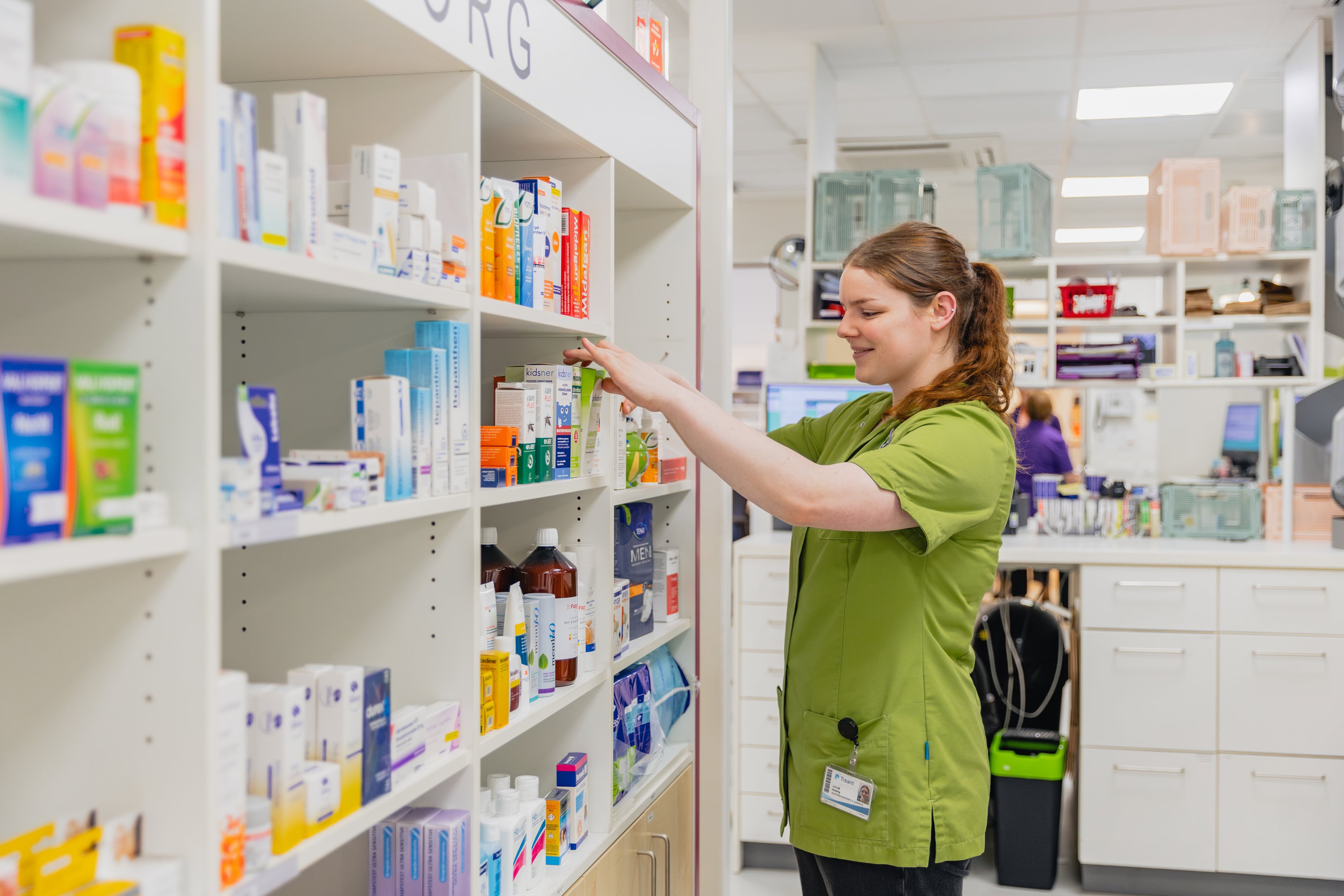 Medewerker apotheek rangschikt medicatie op schappen tijdens stage in gezondheidszorgomgeving