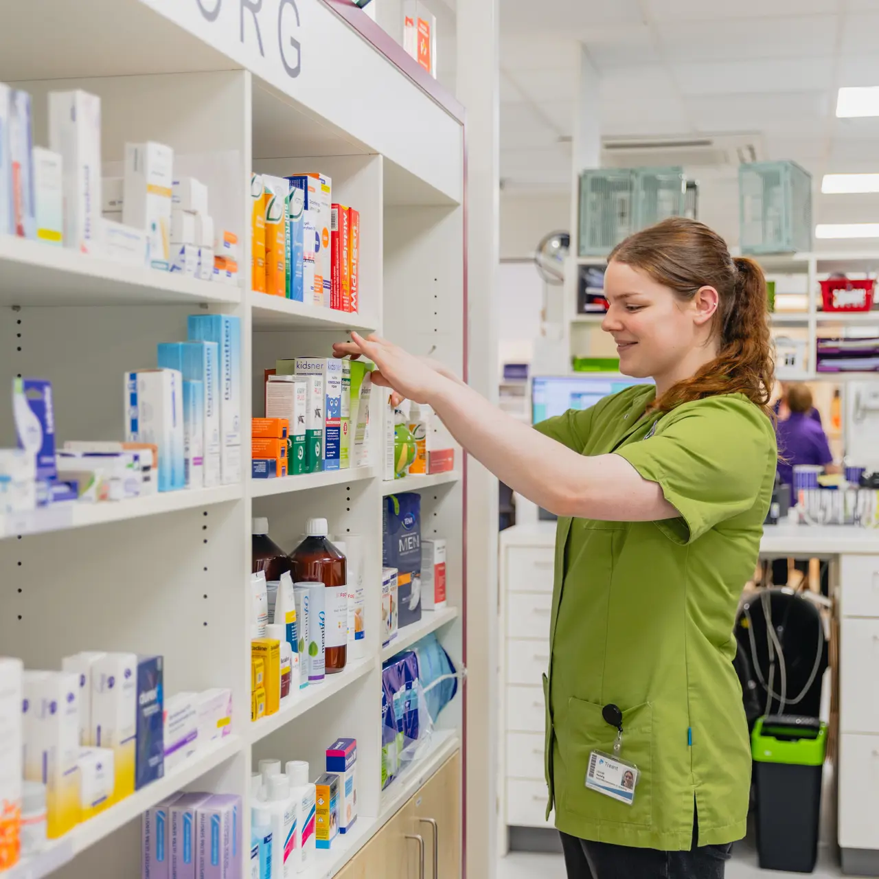 Medewerker apotheek rangschikt medicatie op schappen tijdens stage in gezondheidszorgomgeving