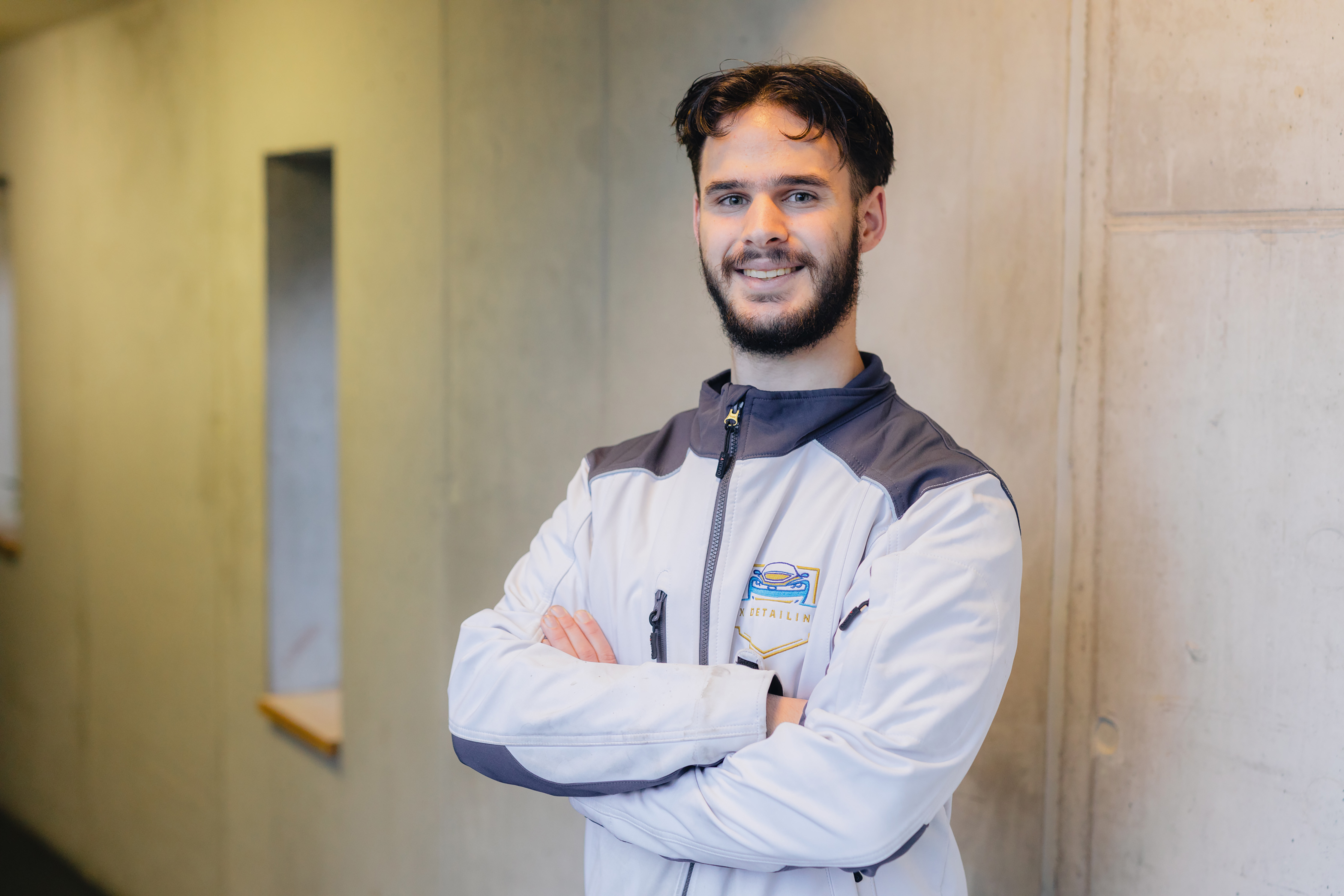 MBO-student met bedrijfskleding staat zelfverzekerd in gang bij opleidingslocatie