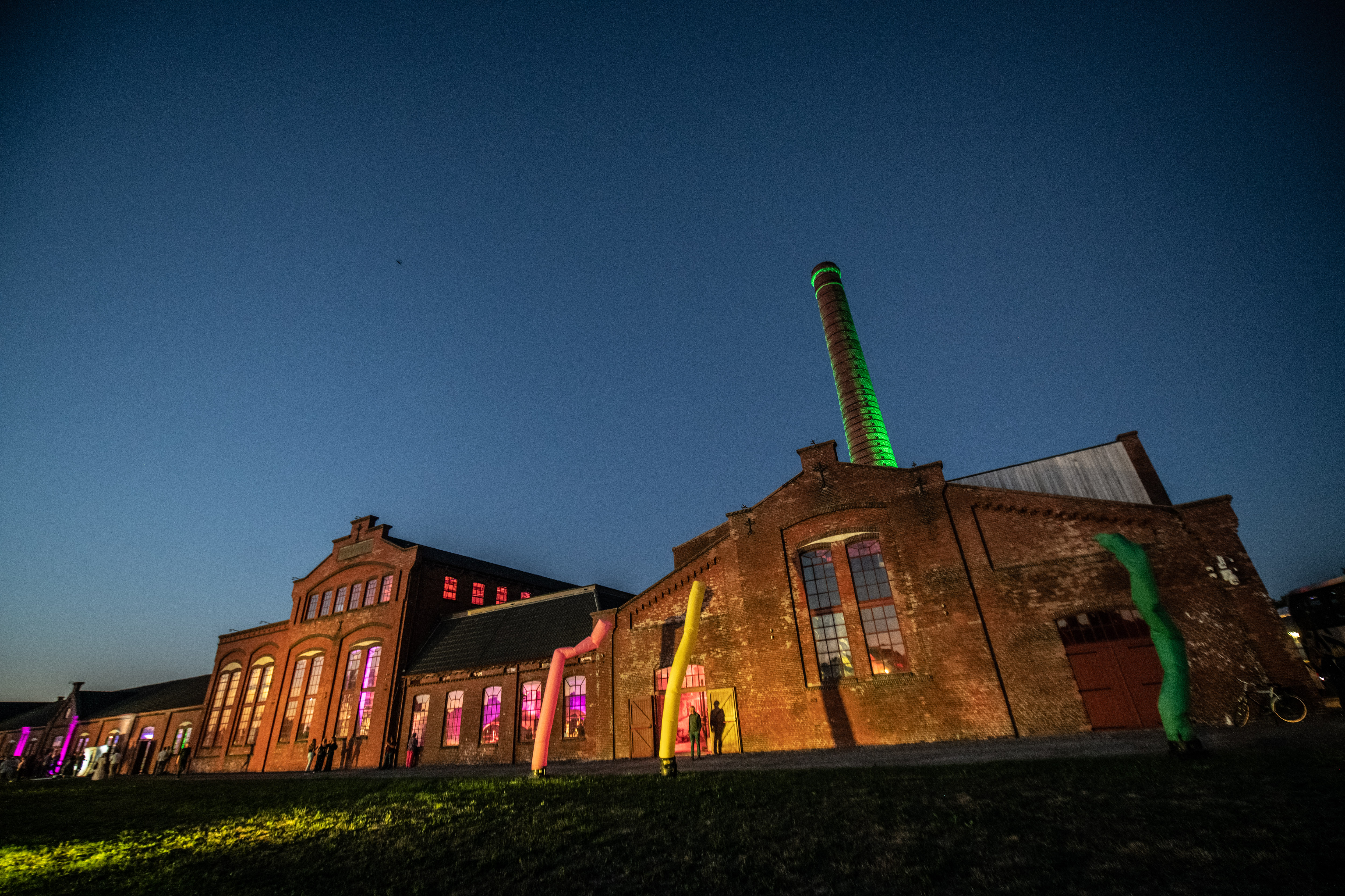 Oud industrieel gebouw verlicht tijdens avond, locatie van Noorderpoort jubileumviering.