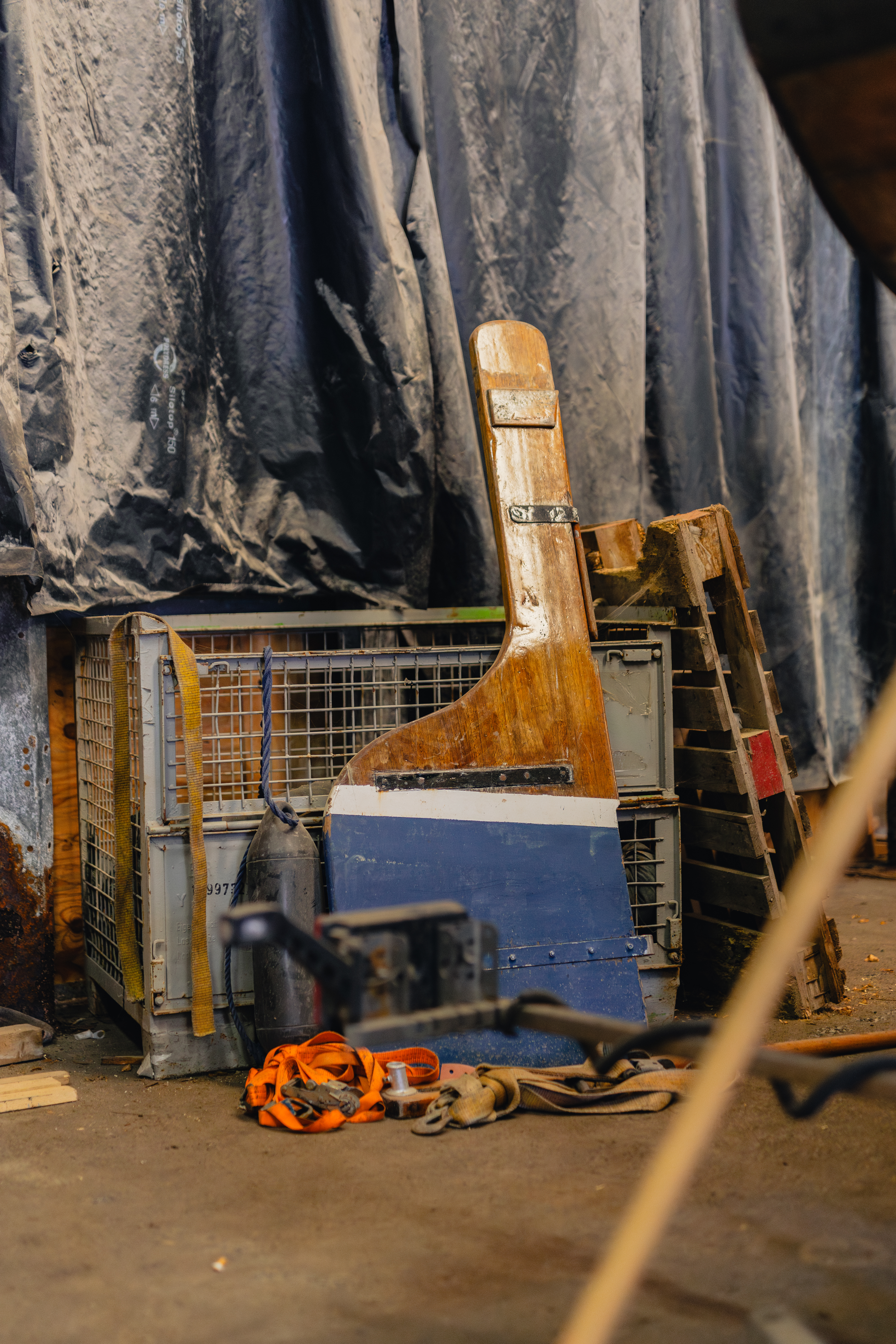 Maritieme werkplek met een houten scheepsroer en zeevaartmateriaal opgeslagen naast elkaar