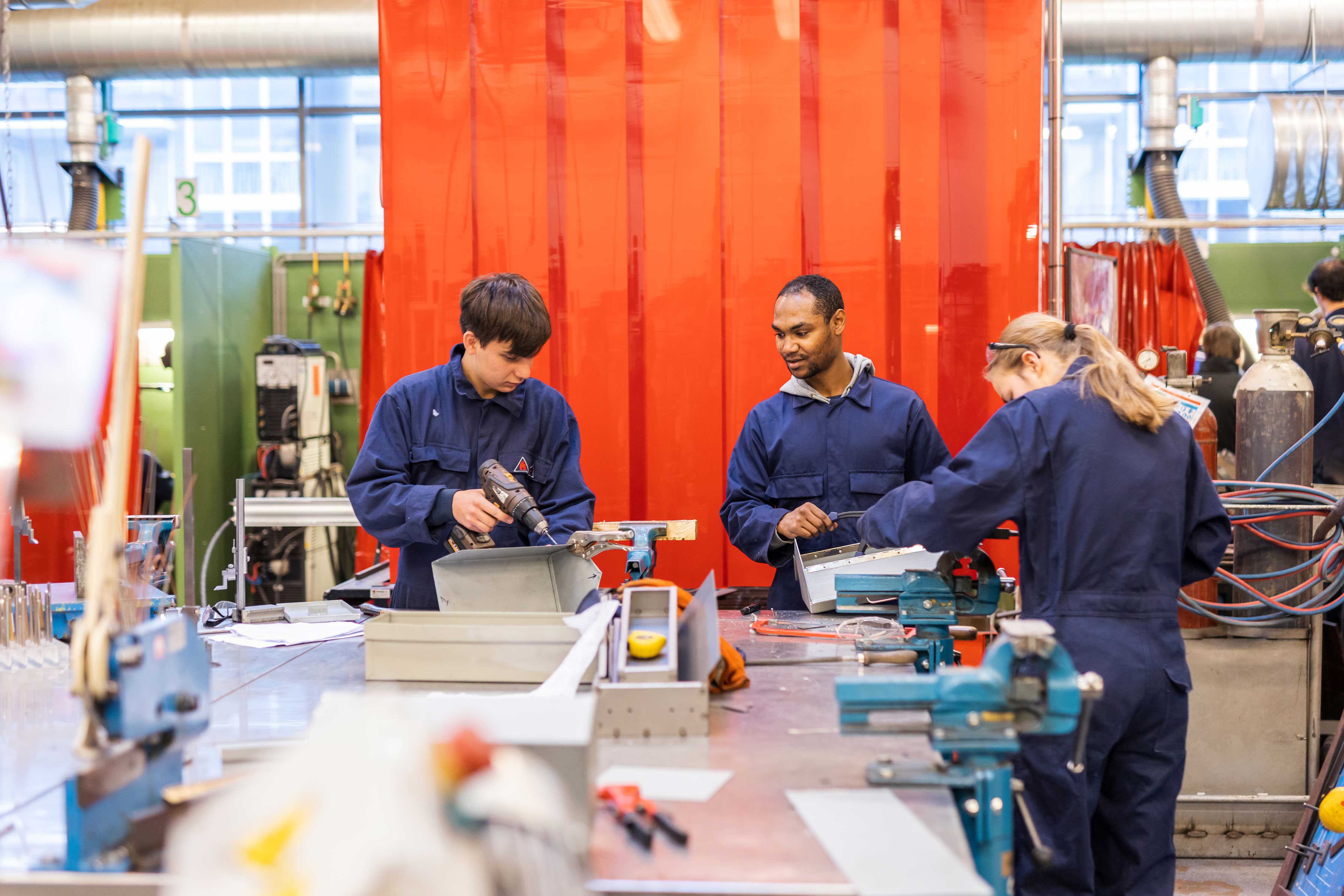 Leerlingen werken samen aan technische opdrachten in een praktijkruimte tijdens een mbo-opleiding.