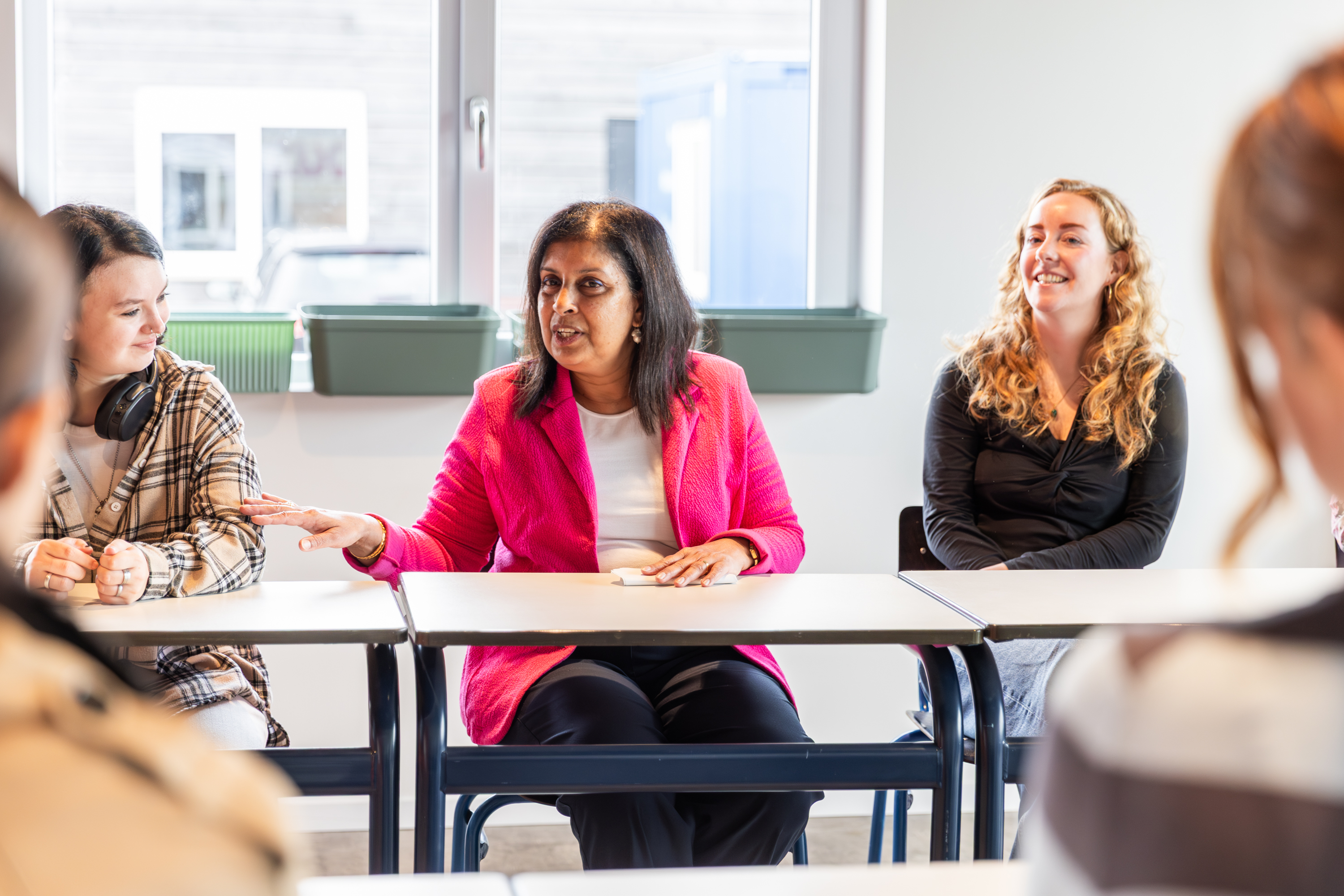 Discussiegroep met docent en studenten in een klaslokaal, gericht op ondersteuning van kwetsbare jongeren