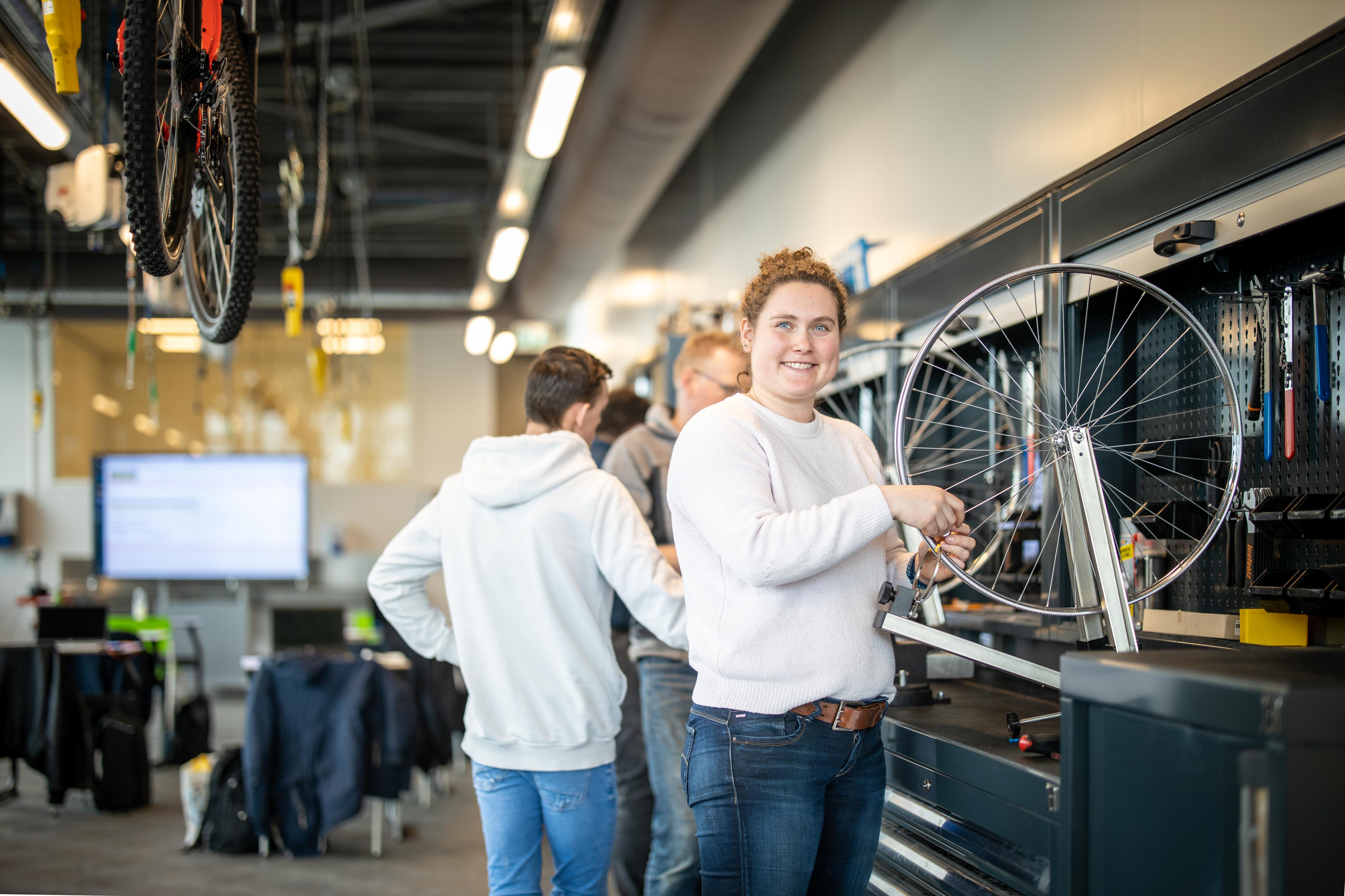 Student werkt aan onderhoud van een fiets in een technische leeromgeving gericht op beroepsopleidingen.