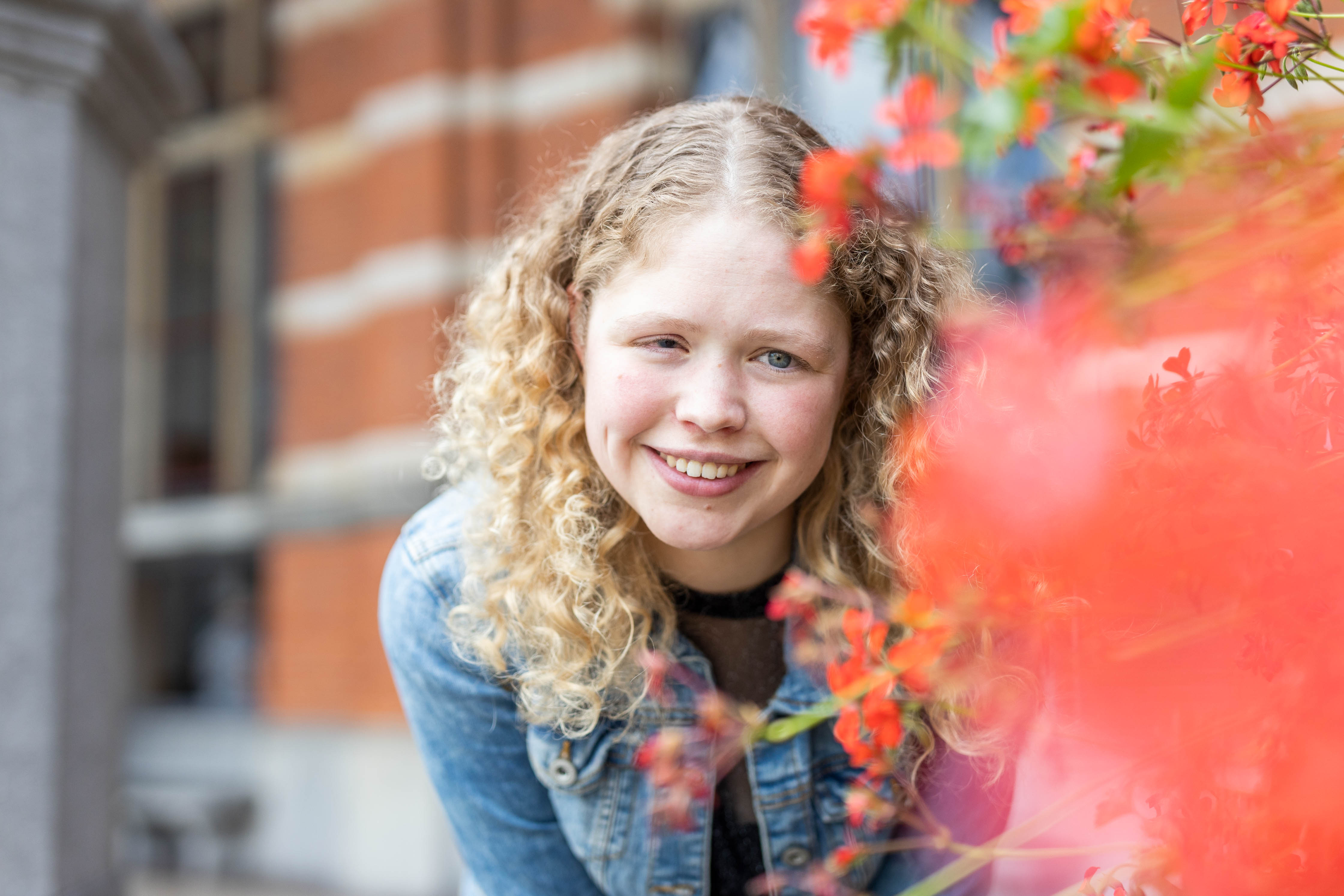 Student kijkt glimlachend en stralend tussen bloemen, illustratie van persoonlijke groei en ontwikkeling