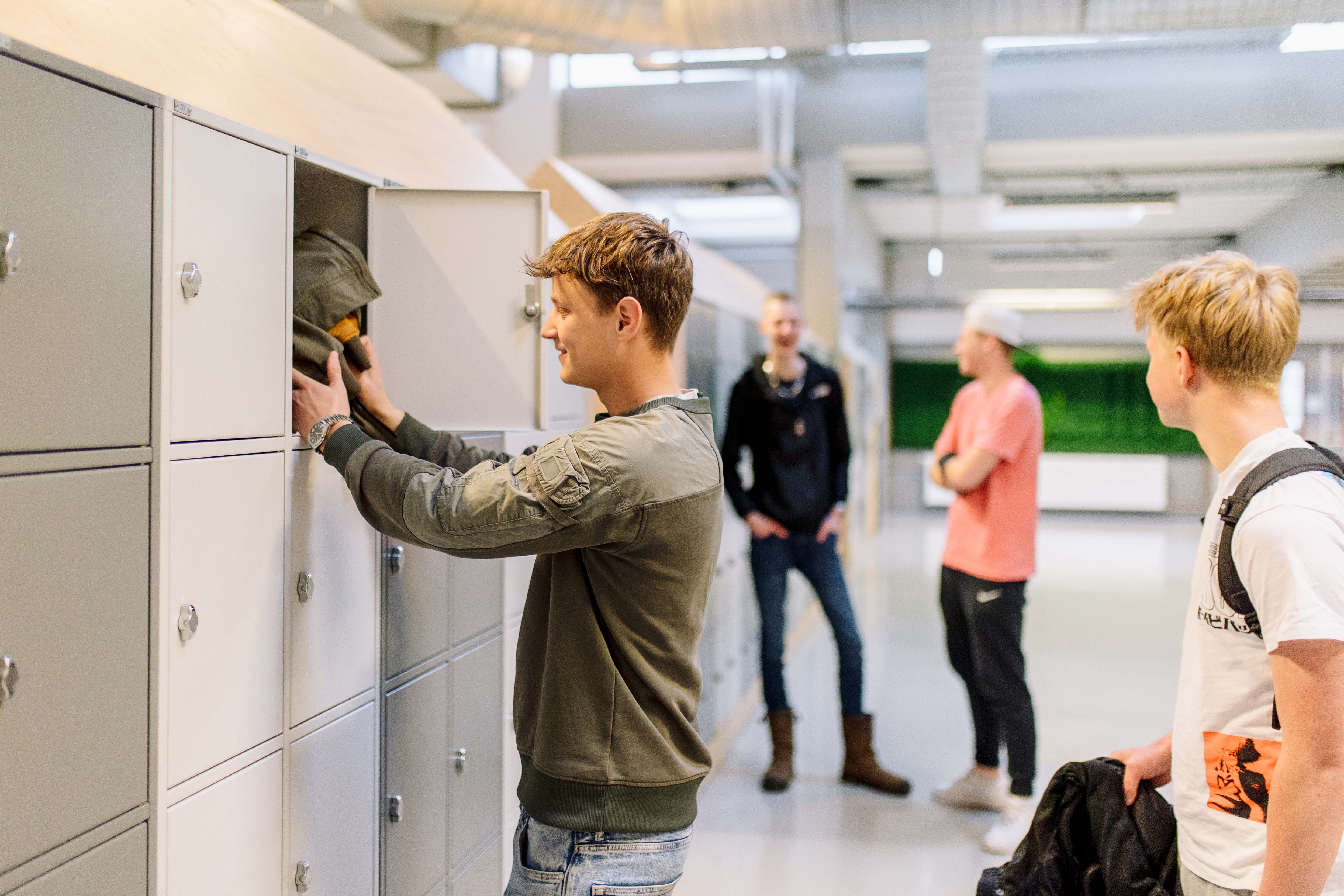 Studenten plaatsen spullen in kluisjes in een onderwijsomgeving tijdens een schooldag.
