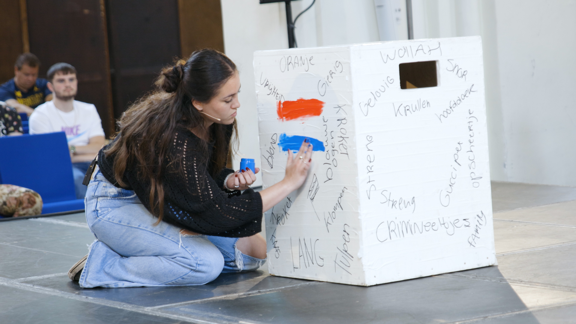 Student schrijft op witte kubus tijdens Keti Koti-event van Noorderpoort in de A-Kerk
