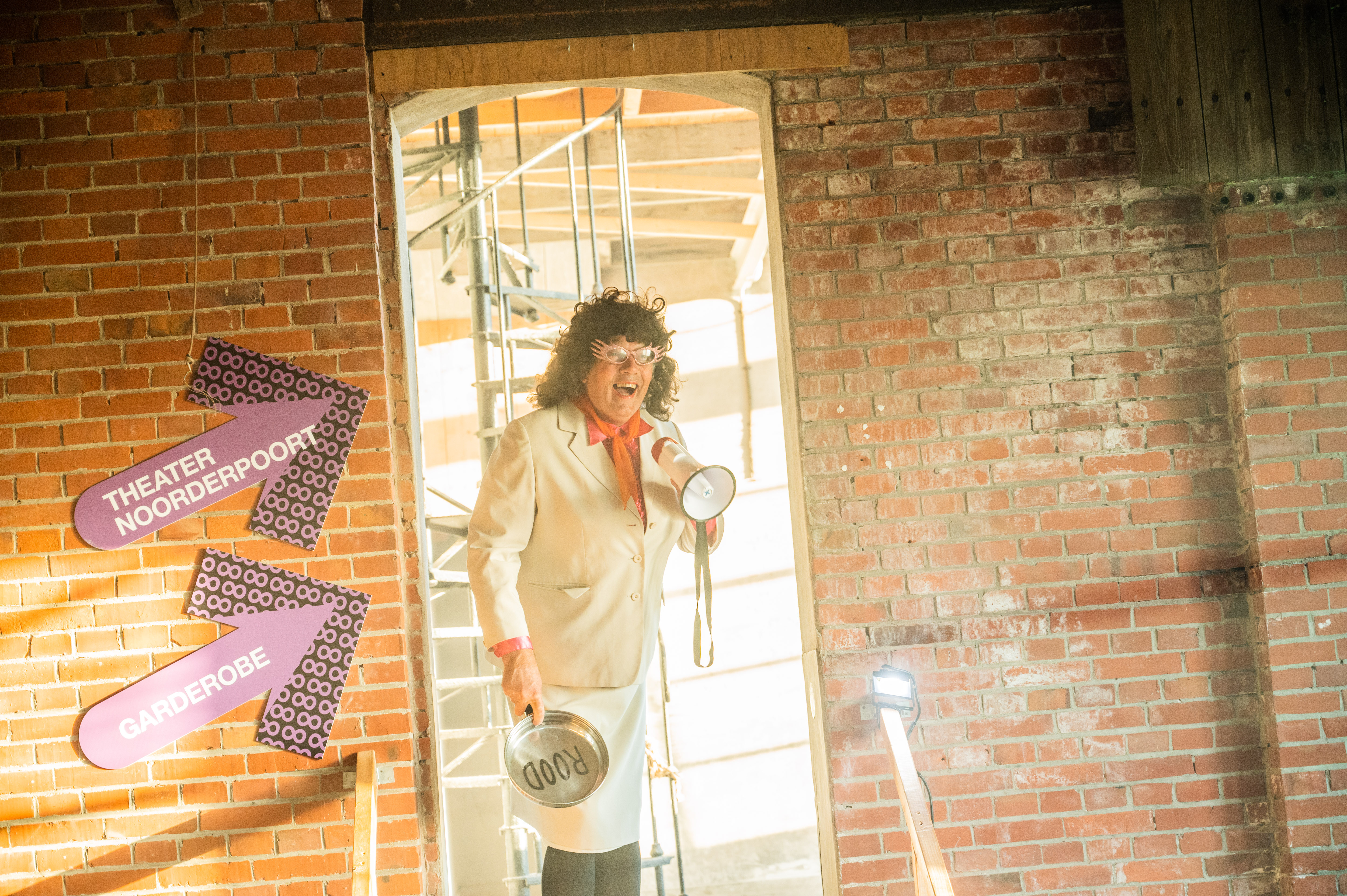 Medewerker maakt aankondiging met megafoon tijdens jubileumviering van Noorderpoort in industriële ruimte