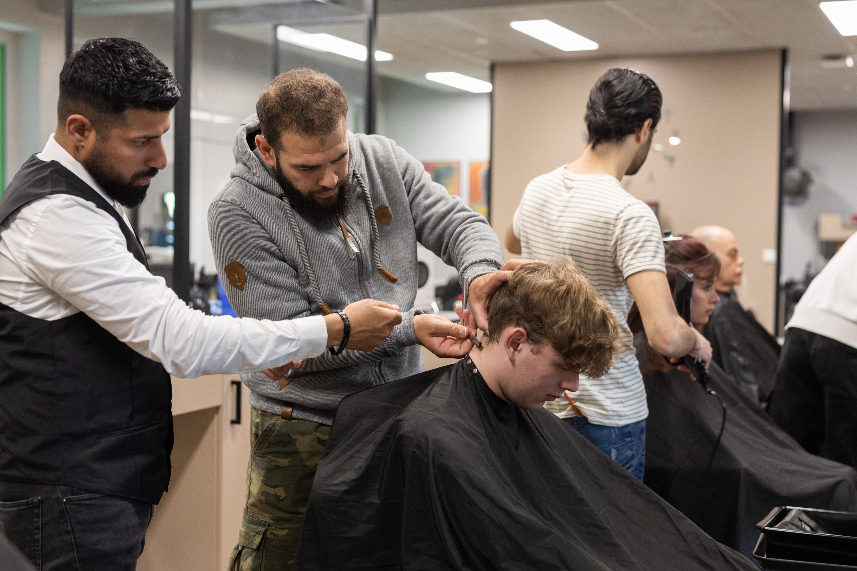 Leerlingen in een praktijkles knippen haar tijdens een speciaal kapperstraject bij Noorderpoort