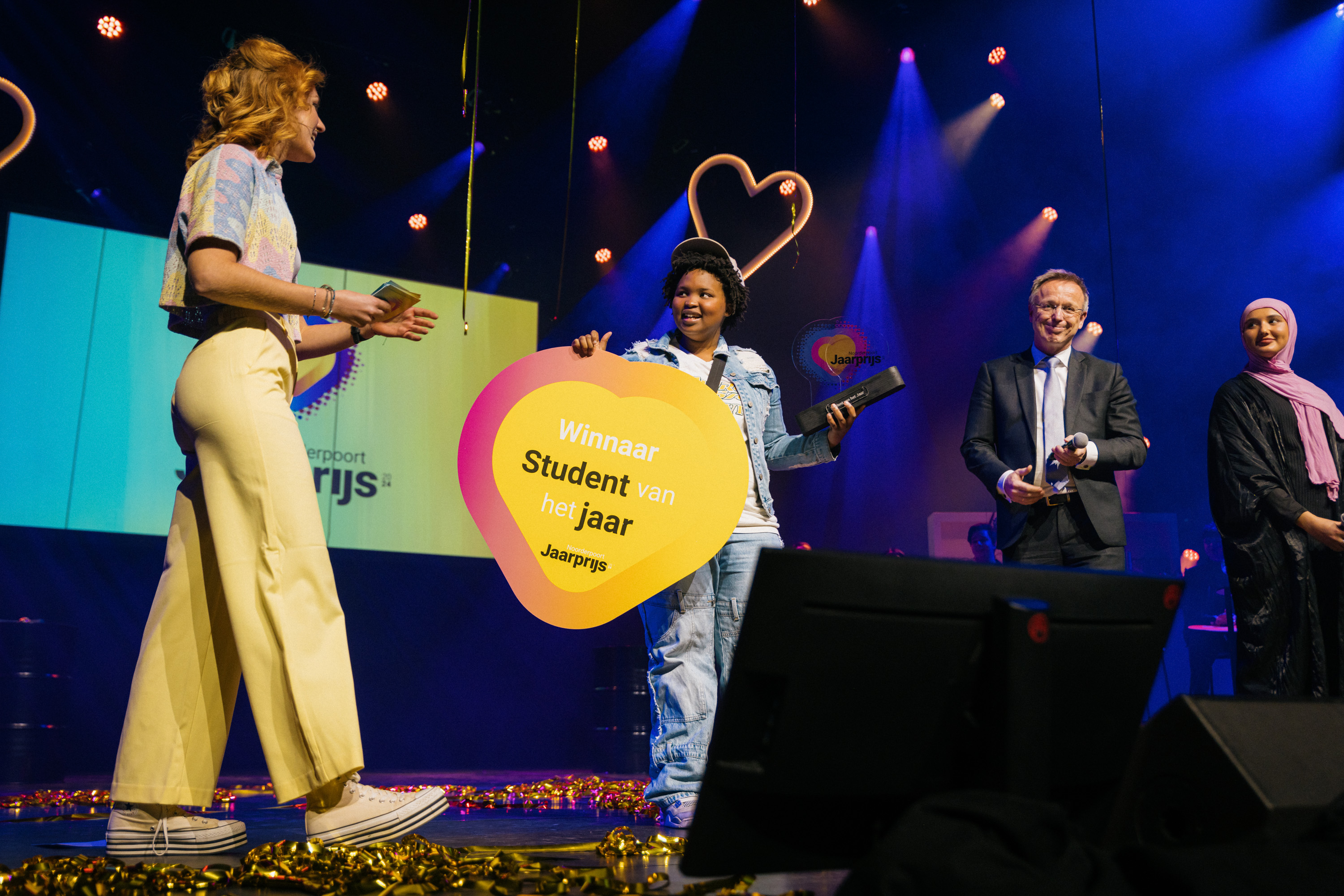Student ontvangt award op podium tijdens uitreiking Noorderpoort Jaarprijs 2024, zichtbaar trots en blij.