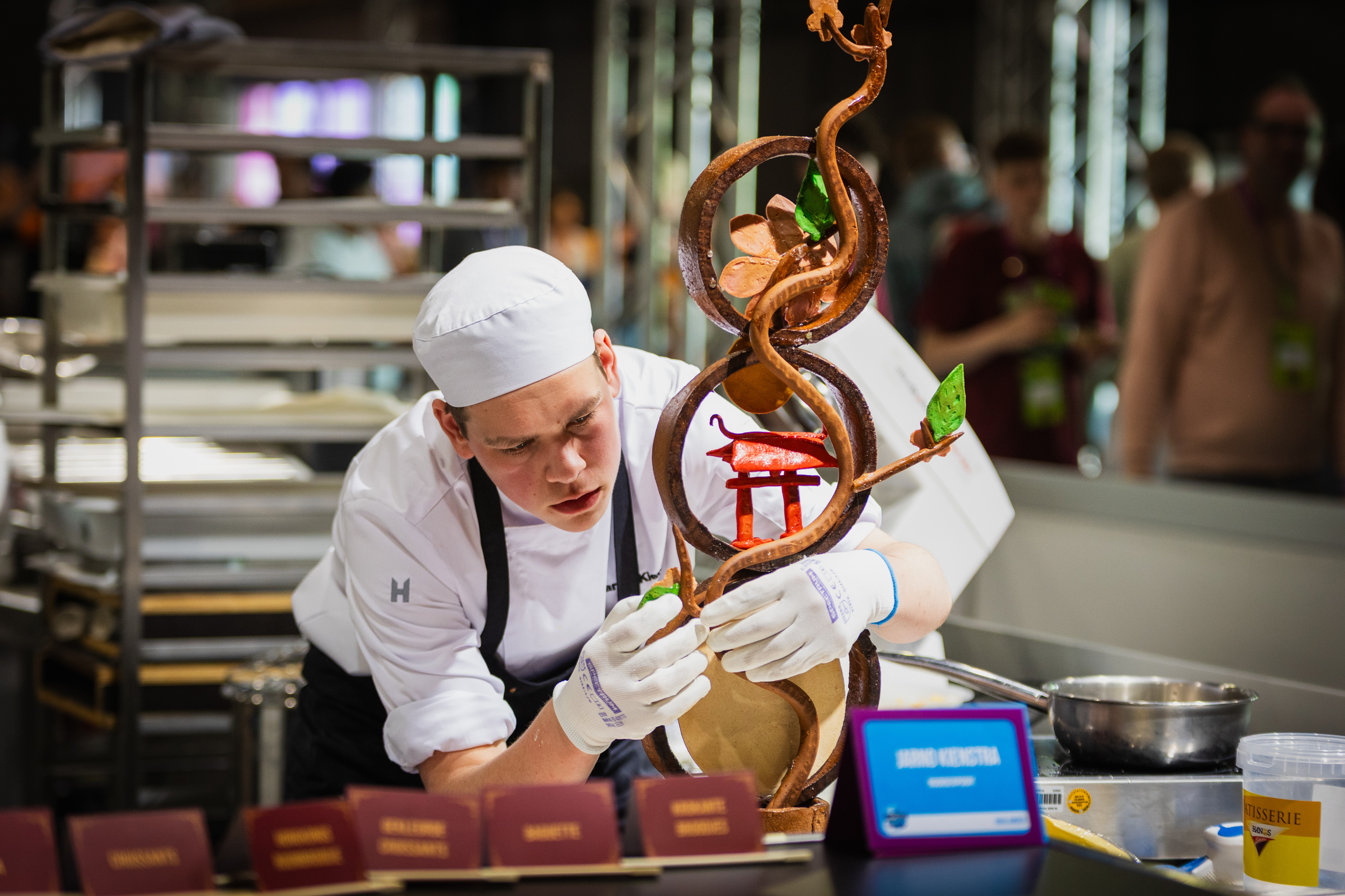 Student bereidt gedetailleerd chocoladekunstwerk voor tijdens landelijke Skills-wedstrijden.
