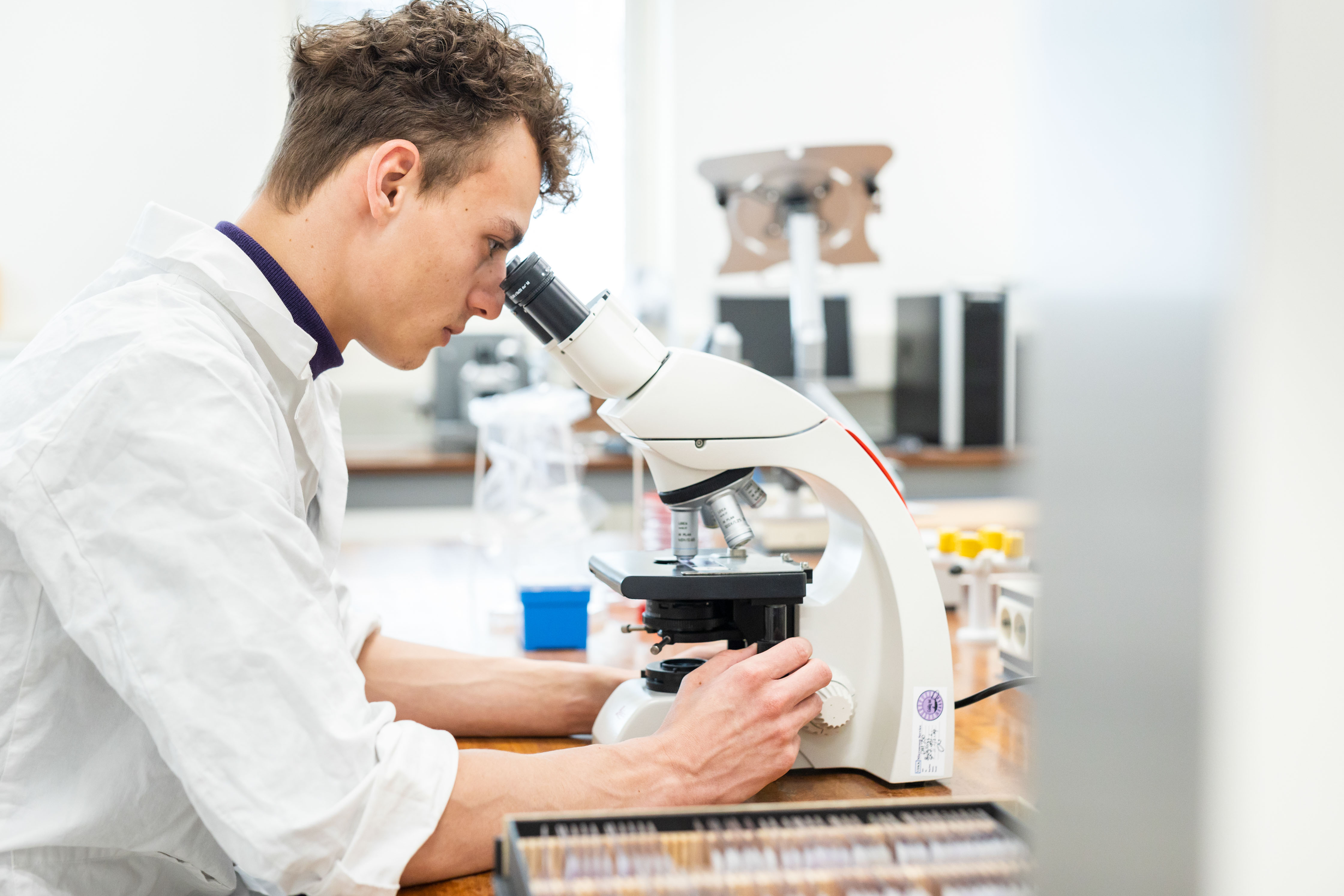 Student werkt geconcentreerd met microscoop in een laboratorium voor procestechniek