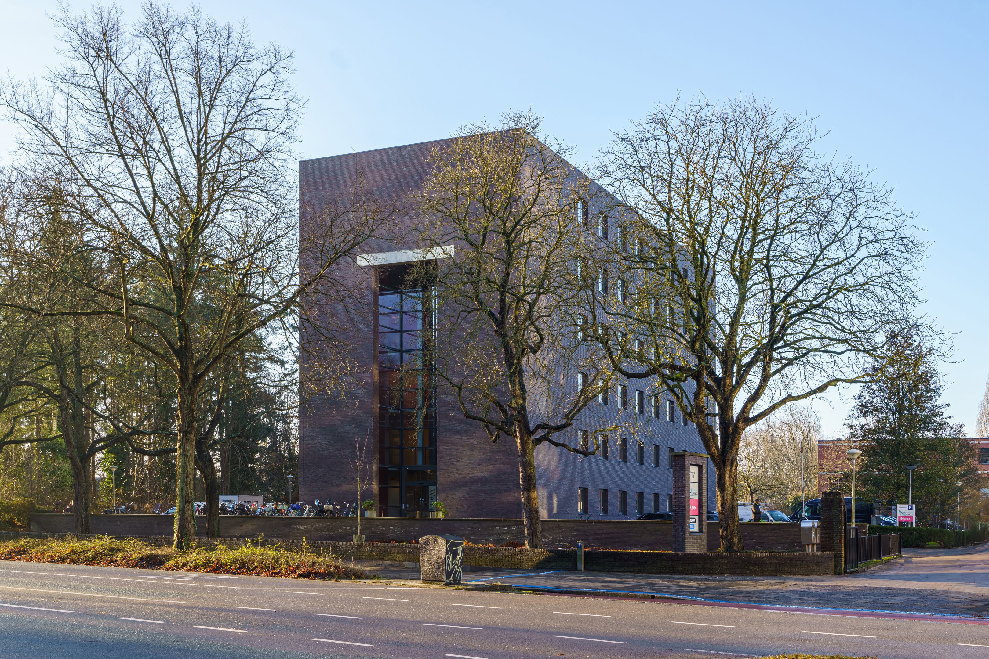 Modern onderwijsgebouw aan de Hereweg 101 in Groningen met zicht op ingang en omliggende bomen