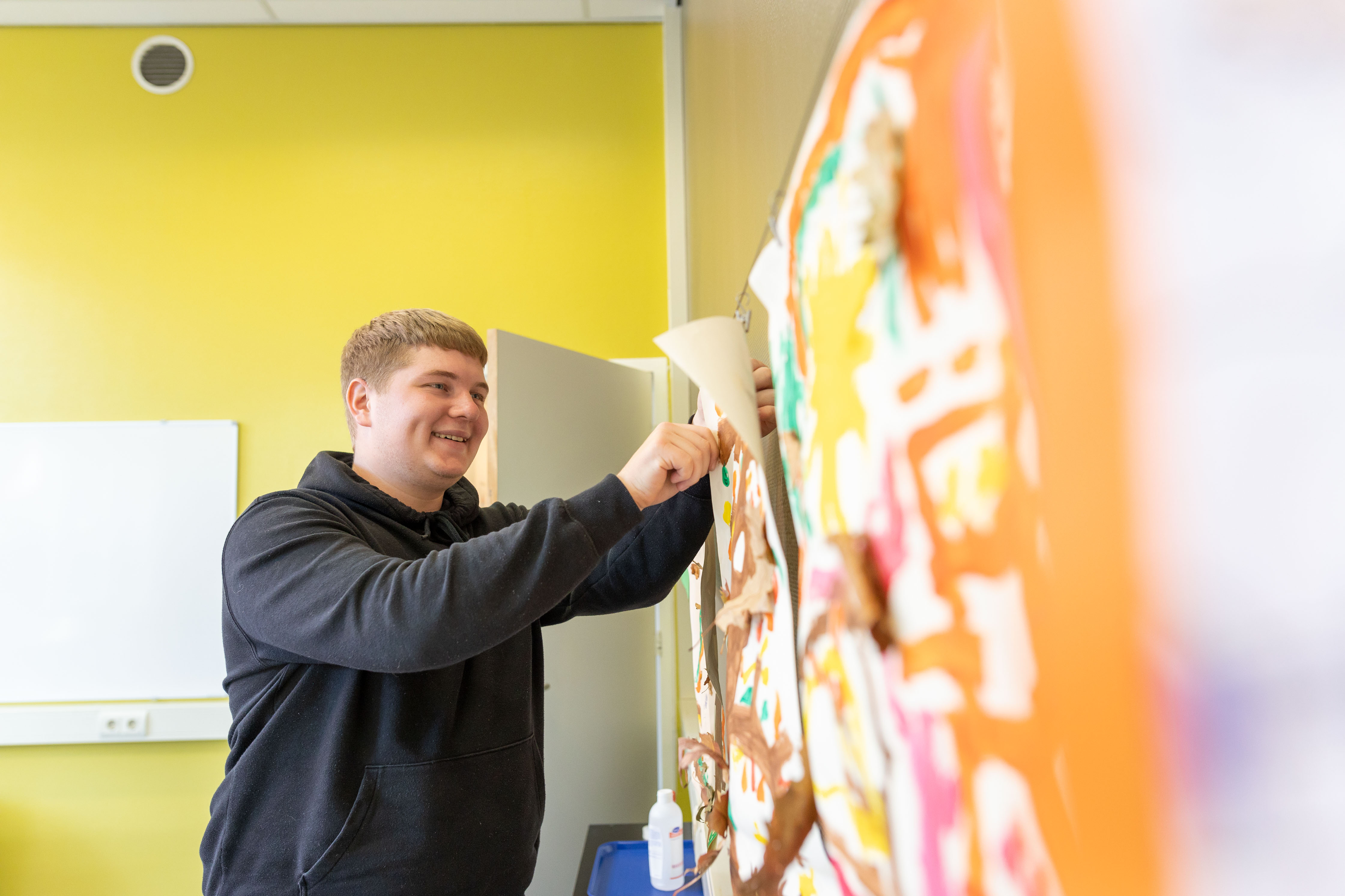 Student die een werkstuk of project presenteert op een prikbord in een leeromgeving