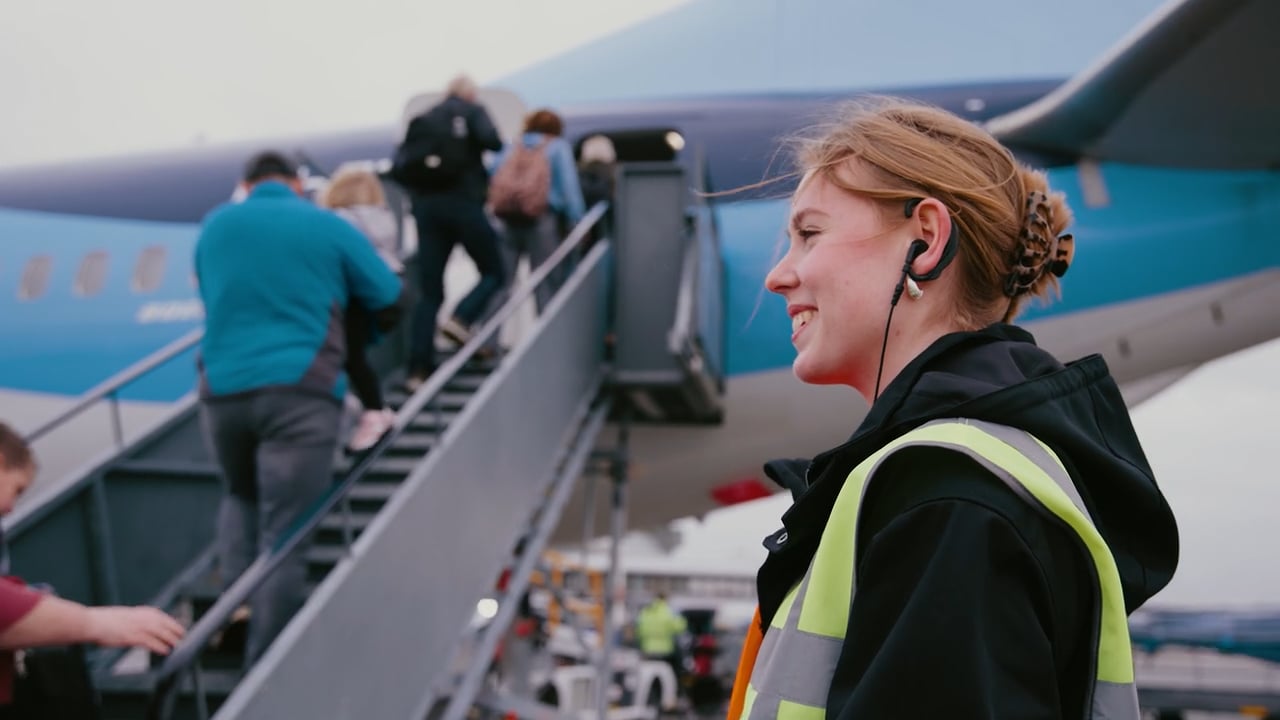 Student luchtvaartdienstverlener begeleidt reizigers bij instappen van vliegtuig op Groningen Airport Eelde