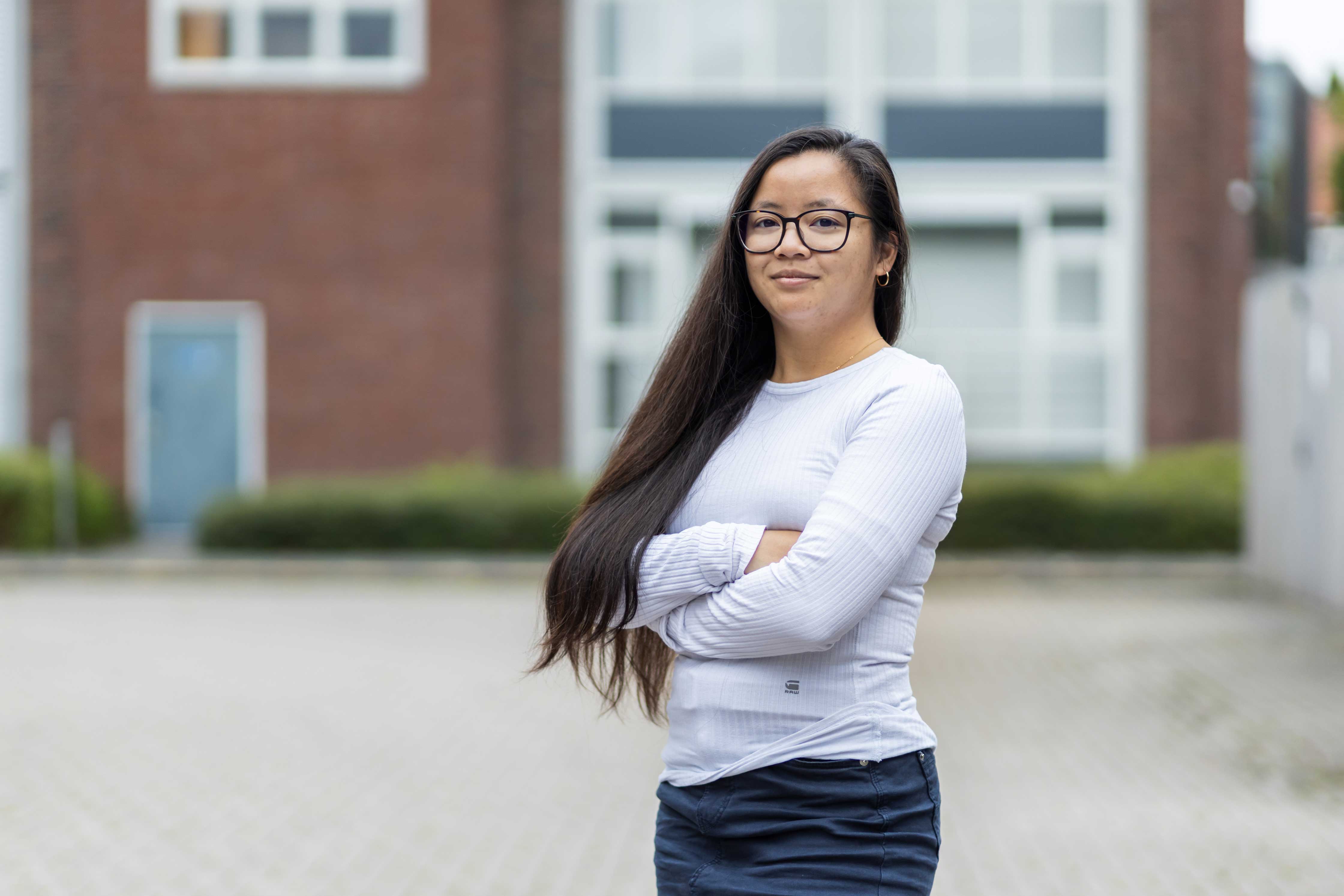 Student met lange haren staat zelfverzekerd buiten een schoolgebouw van Noorderpoort.