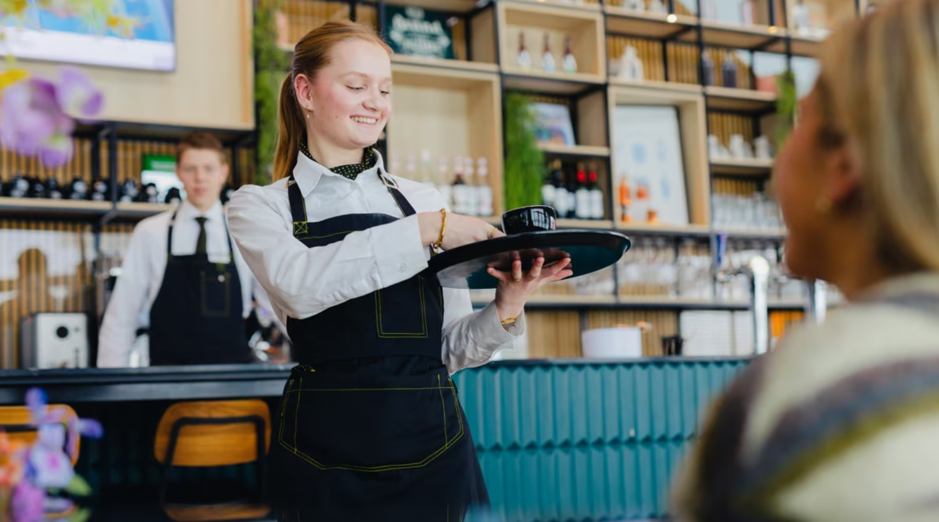 Student serveert drankjes in een horecaomgeving, oefent gastvrijheid en klantgerichtheid