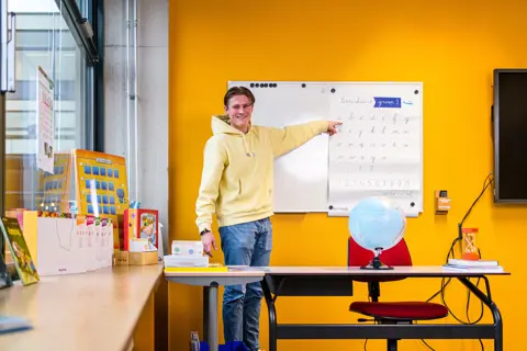 Student wijzend naar een whiteboard met schrijfoefeningen in een klaslokaal van Noorderpoort