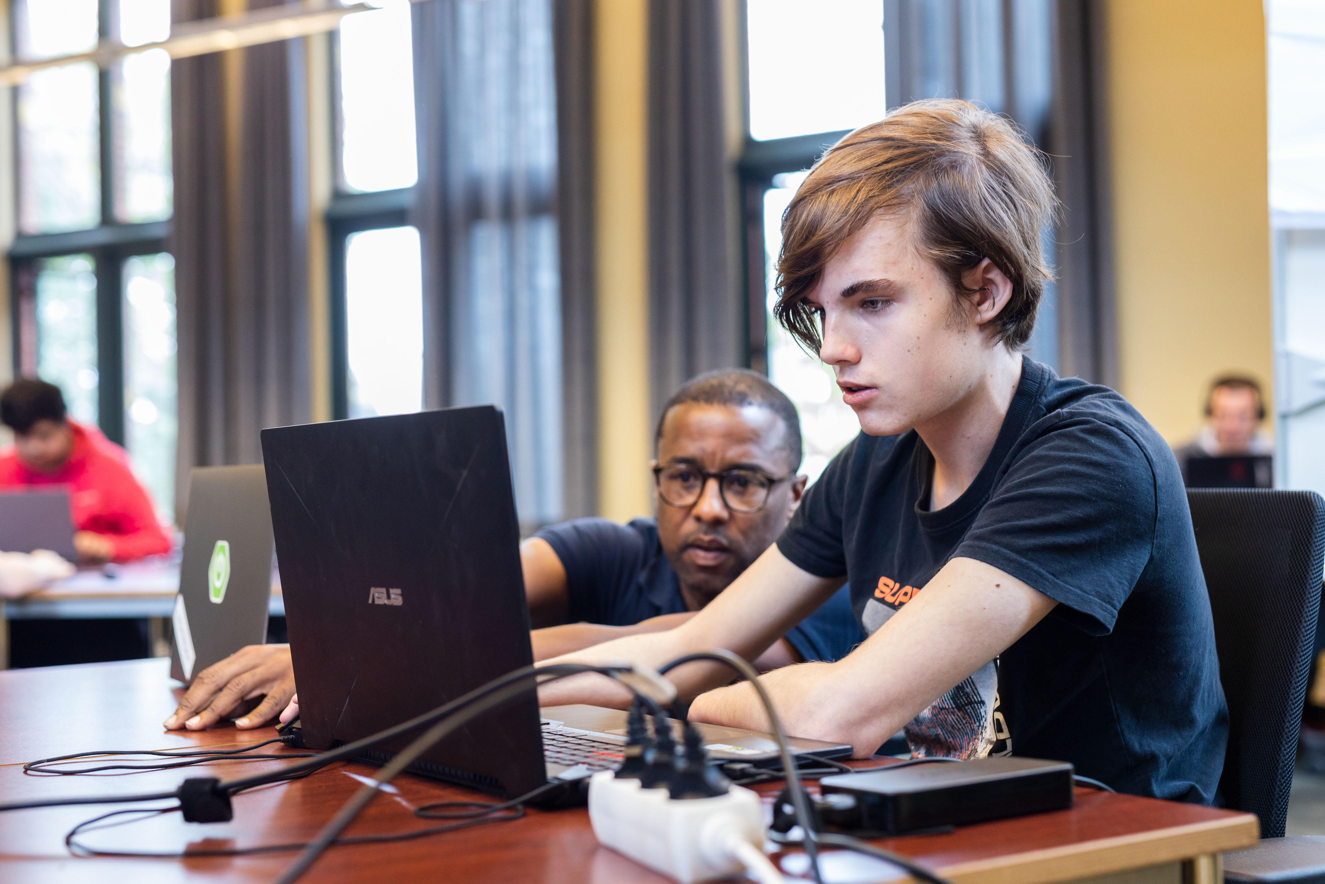Student en docent werken samen aan een IT-project met laptop in een klaslokaal van Noorderpoort