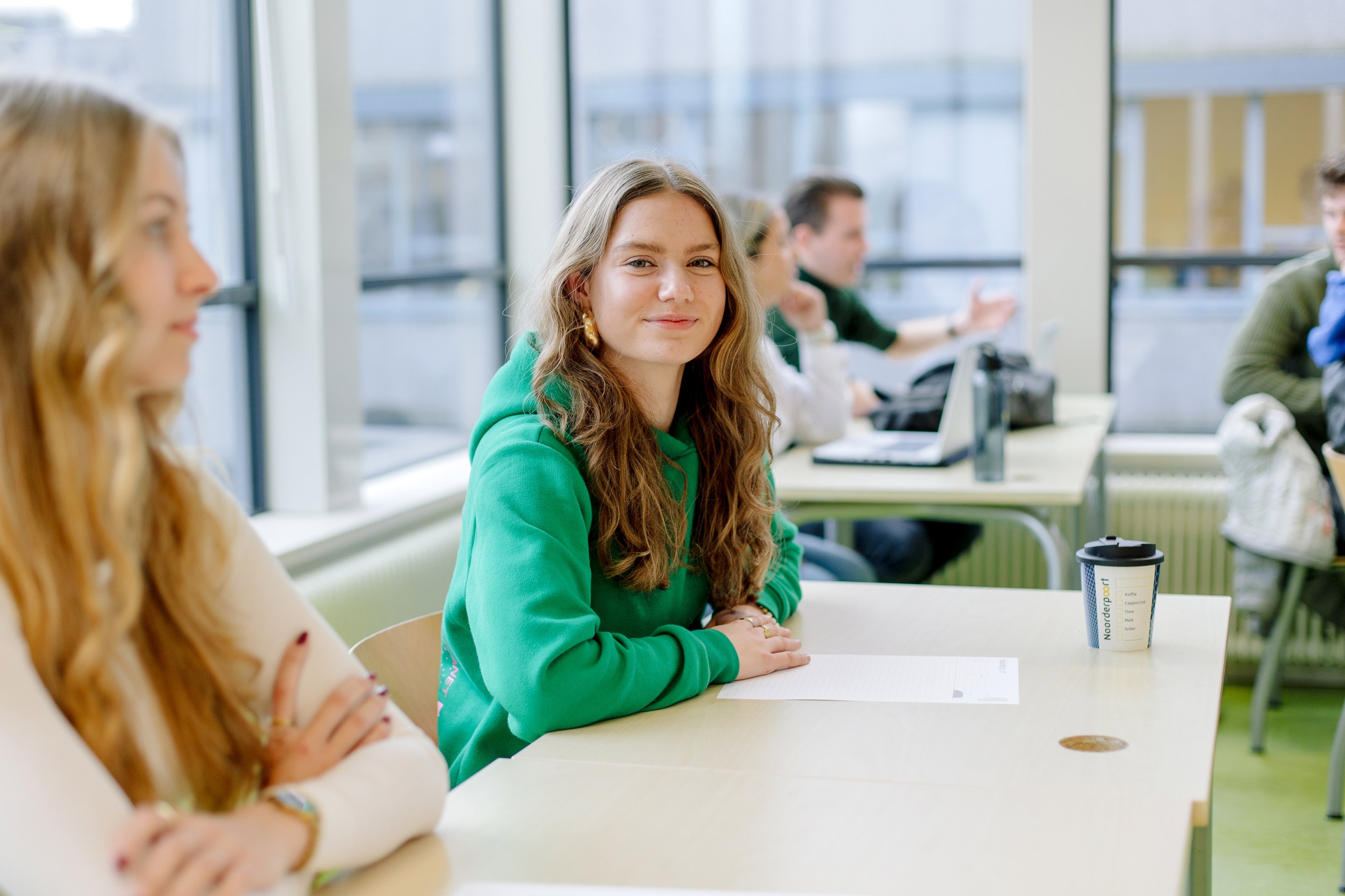 Studenten werken in een moderne leeromgeving aan opdrachten en volgen onderwijs gezamenlijk.