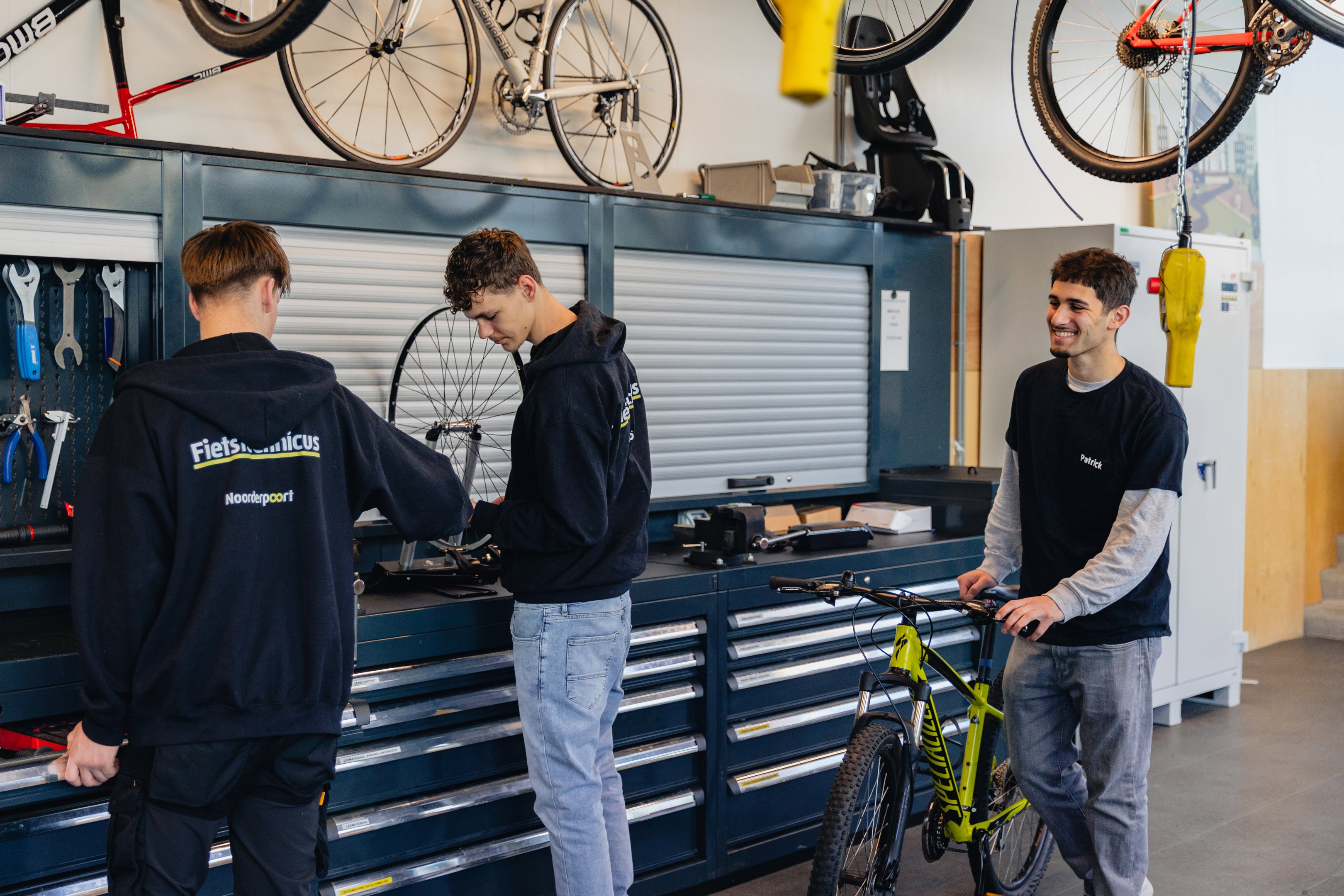 Studenten repareren en onderhouden fietsen in een goed uitgeruste werkplaats bij Noorderpoort.