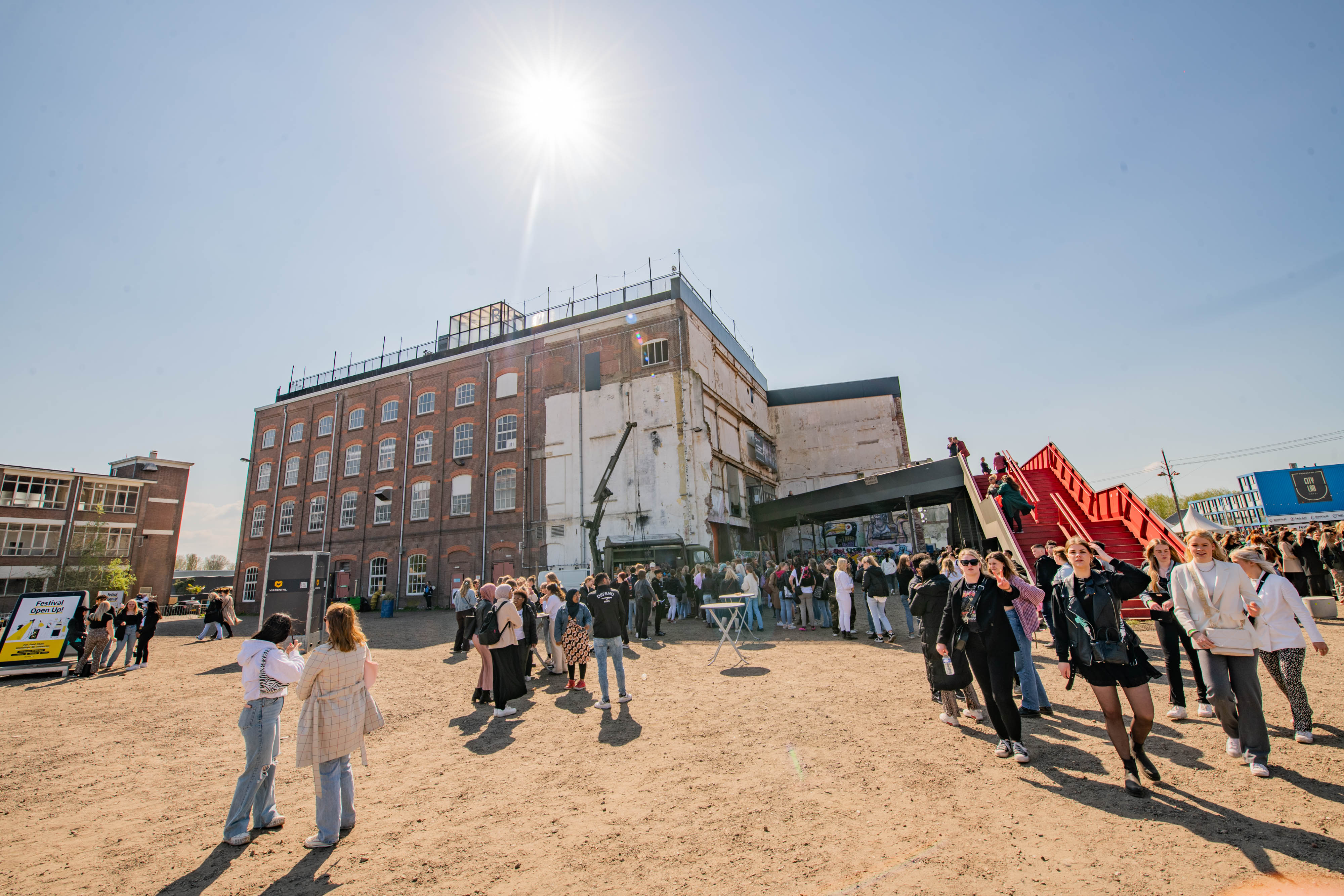 Groep mbo-studenten verzamelt bij industrieel gebouw tijdens festival over praktische levensvaardigheden