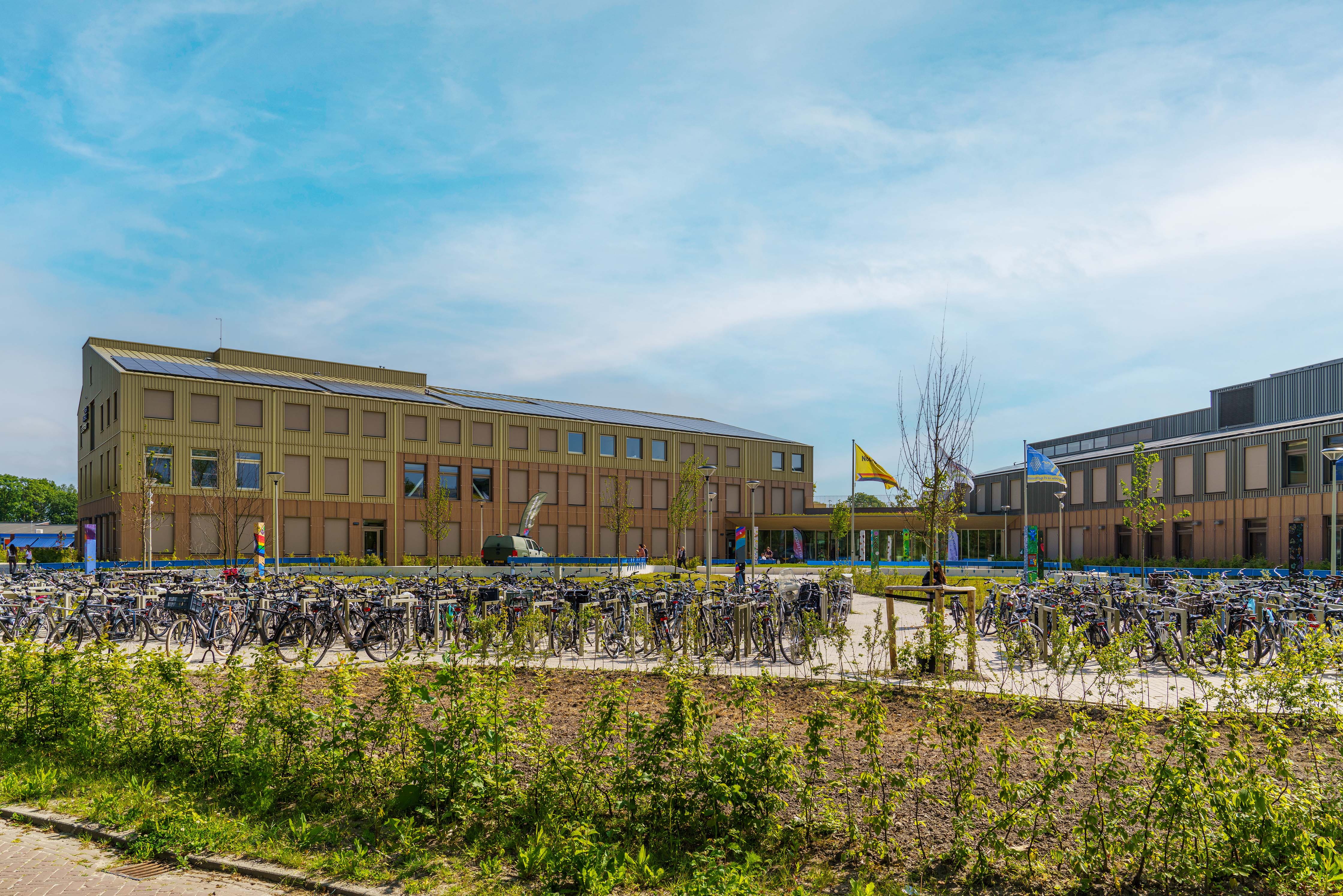 Noorderpoort gebouw aan Pastorielaan in Appingedam met fietsenrekken en vlaggen bij de ingang