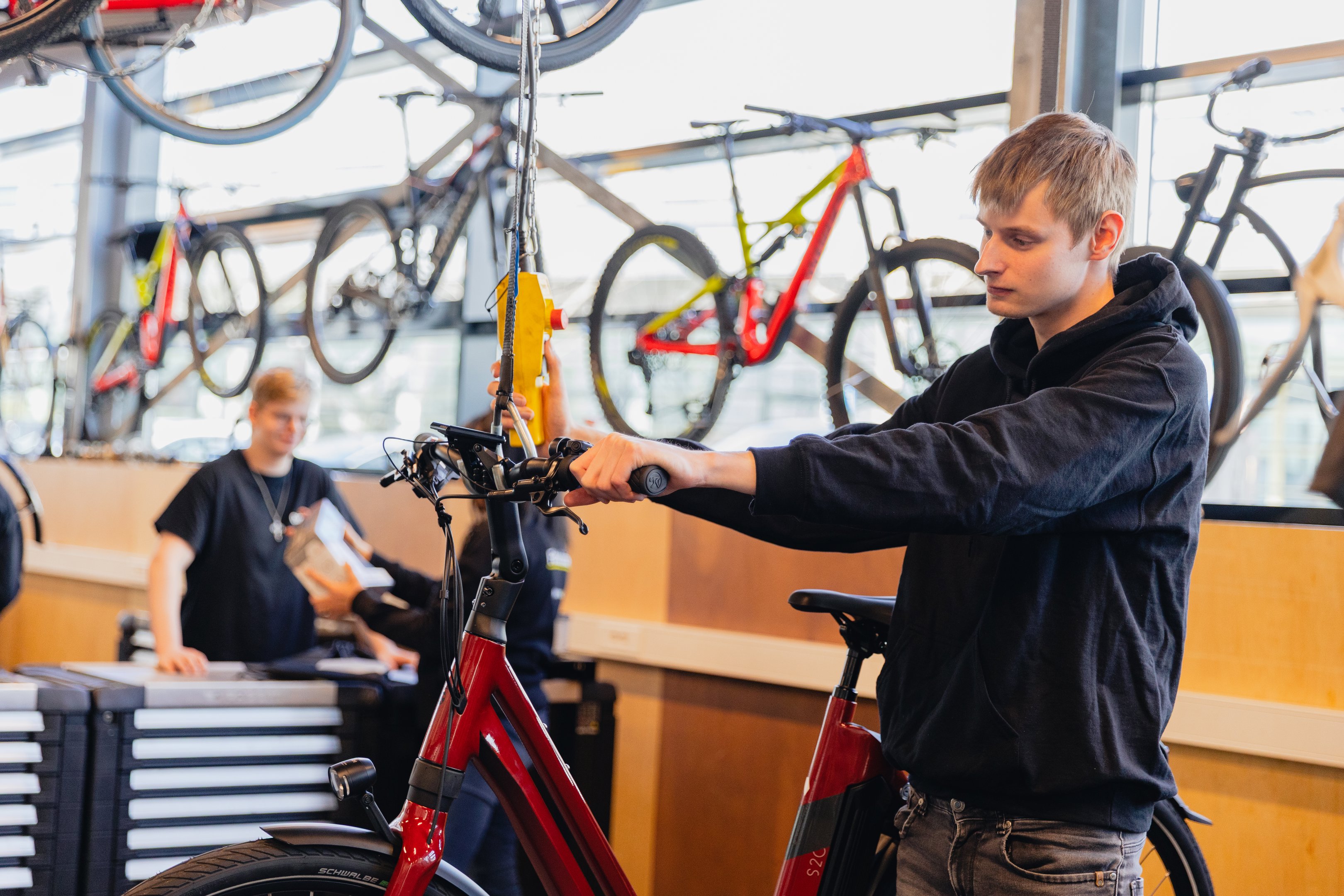 Student werkt aan reparatie van een elektrische fiets in een goed uitgeruste praktijkruimte van een techniekopleiding.