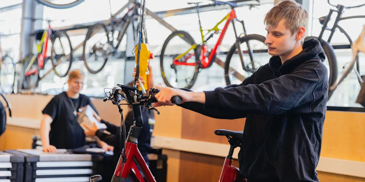 Student werkt aan reparatie van een elektrische fiets in een goed uitgeruste praktijkruimte van een techniekopleiding.