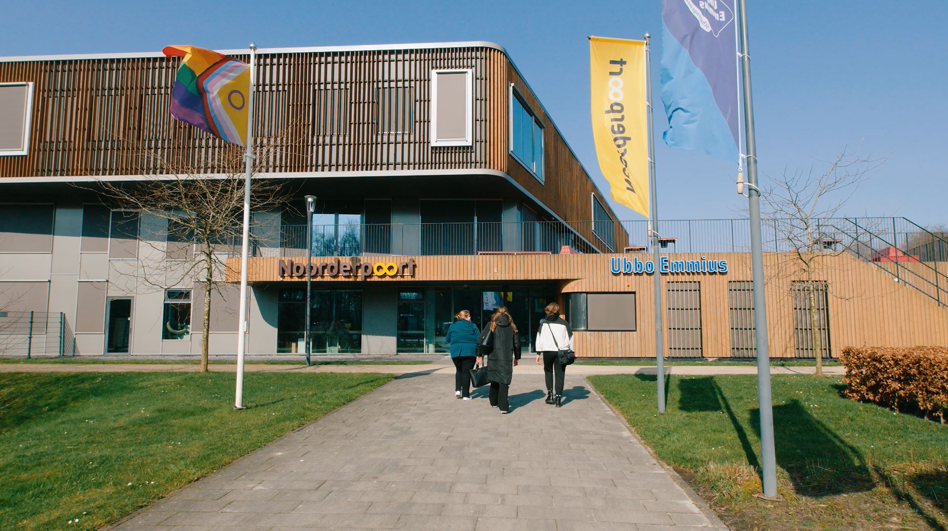 Gebouw van Noorderpoort Ubbo Emmius met drie personen die naar de ingang lopen aan Sportparklaan 5 Stadskanaal