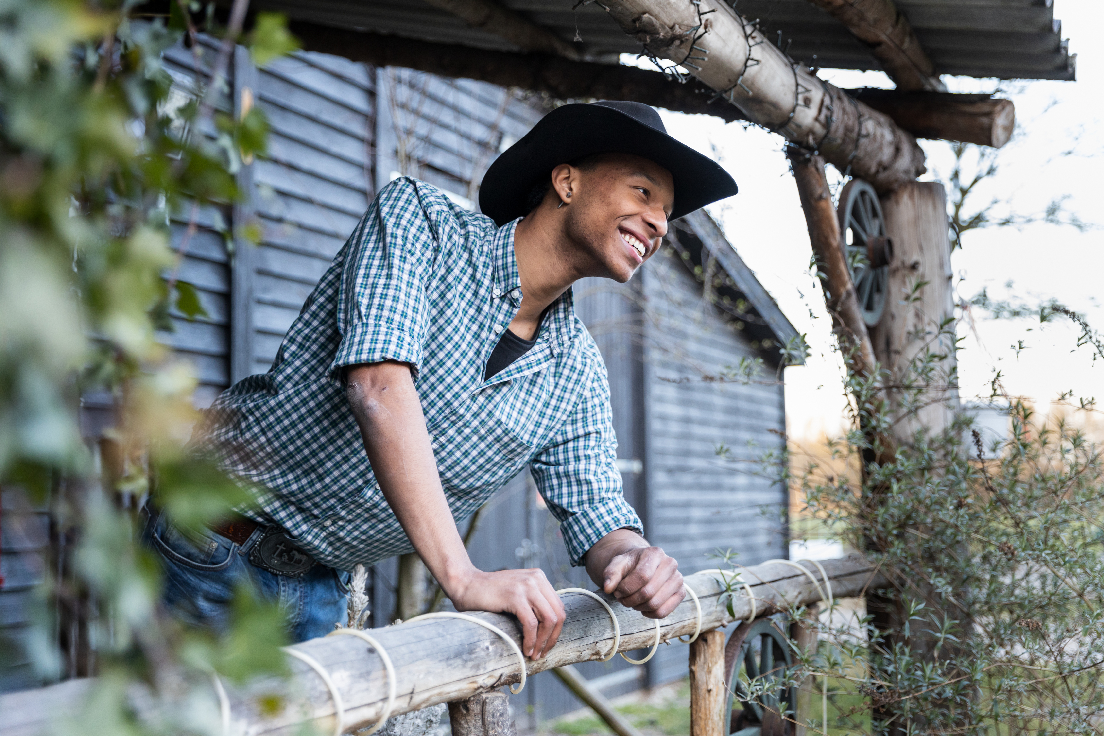 Student die in westernkleding over een houten hek leunt, passend bij het thema van fietsen en cowboy.