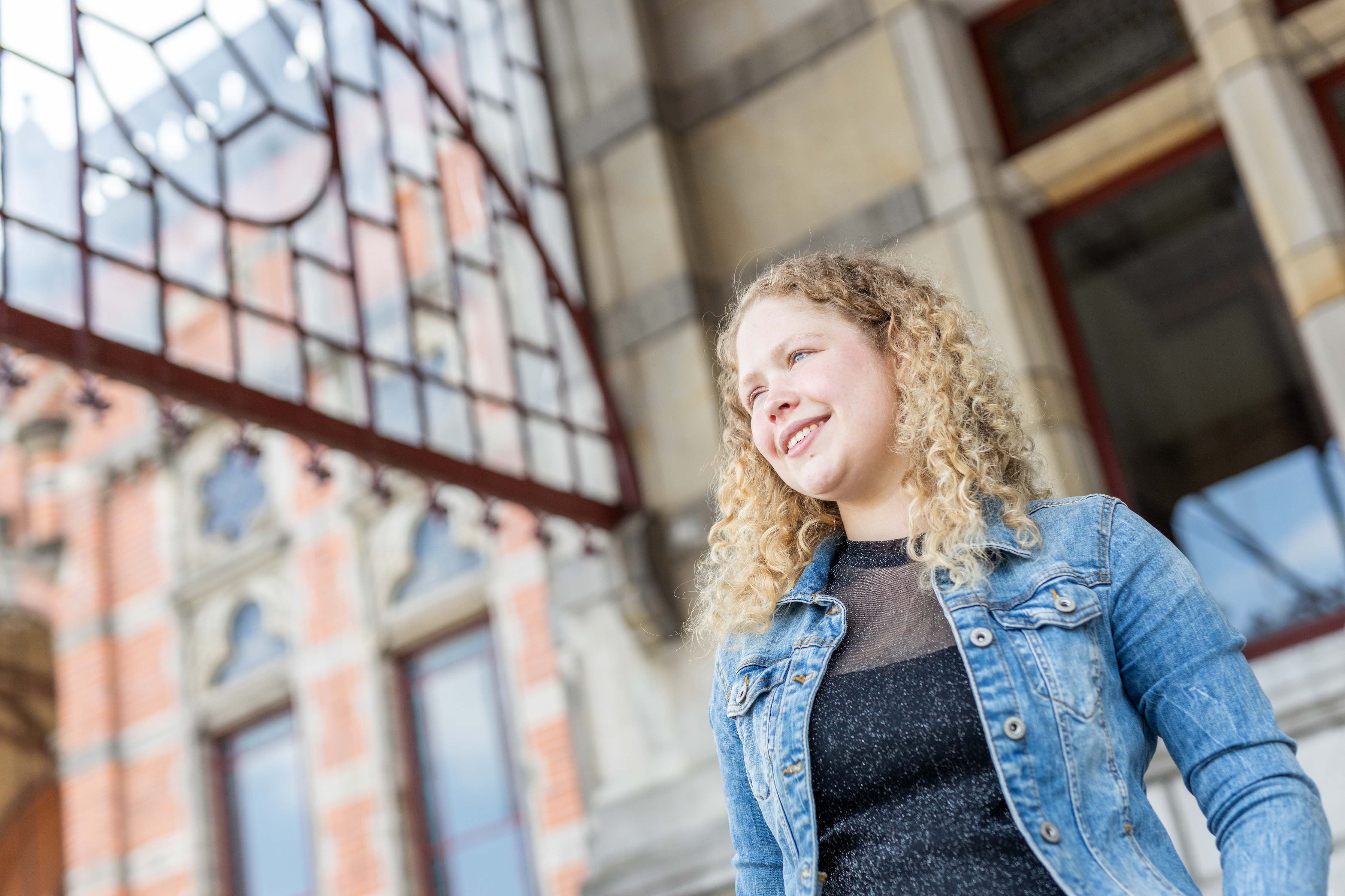 Een student kijkt verwachtingsvol richting een gebouw van Noorderpoort, symbool voor persoonlijke groei en ontwikkeling.