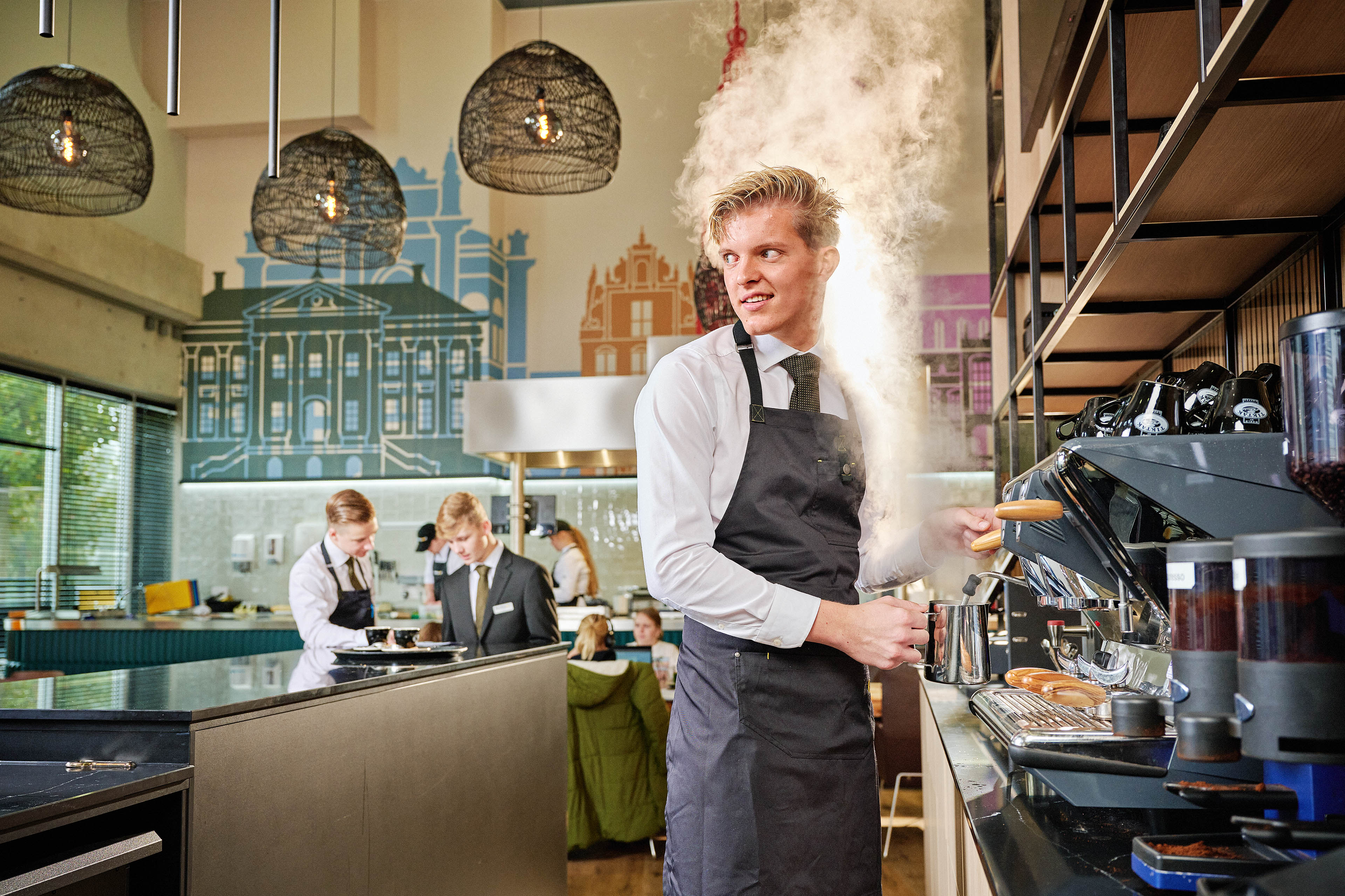 Leerling barista bereidt koffie met espressomachine in praktijkleerbedrijf van Noorderpoort.
