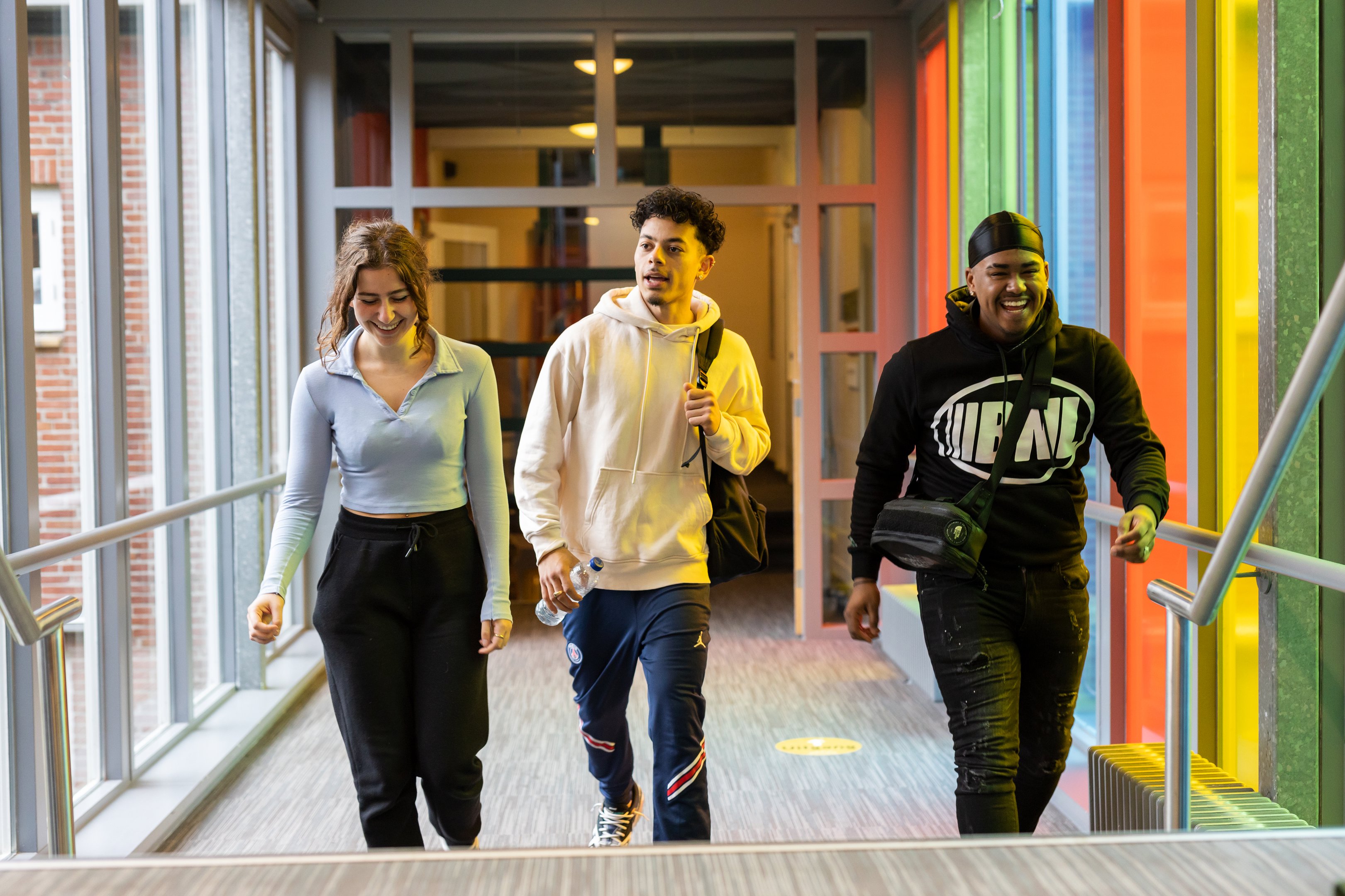 Drie mbo-studenten lopen samen door een schoolgebouw en zijn in gesprek tijdens hun pauze