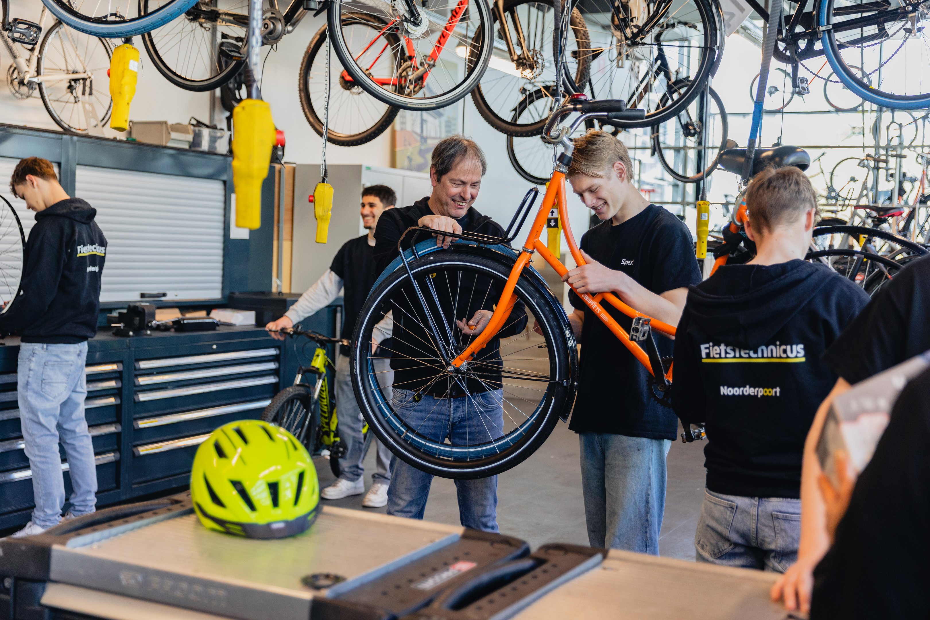Leerlingen en docent repareren samen een fiets tijdens de opleiding fietstechnicus in een werkplaats.