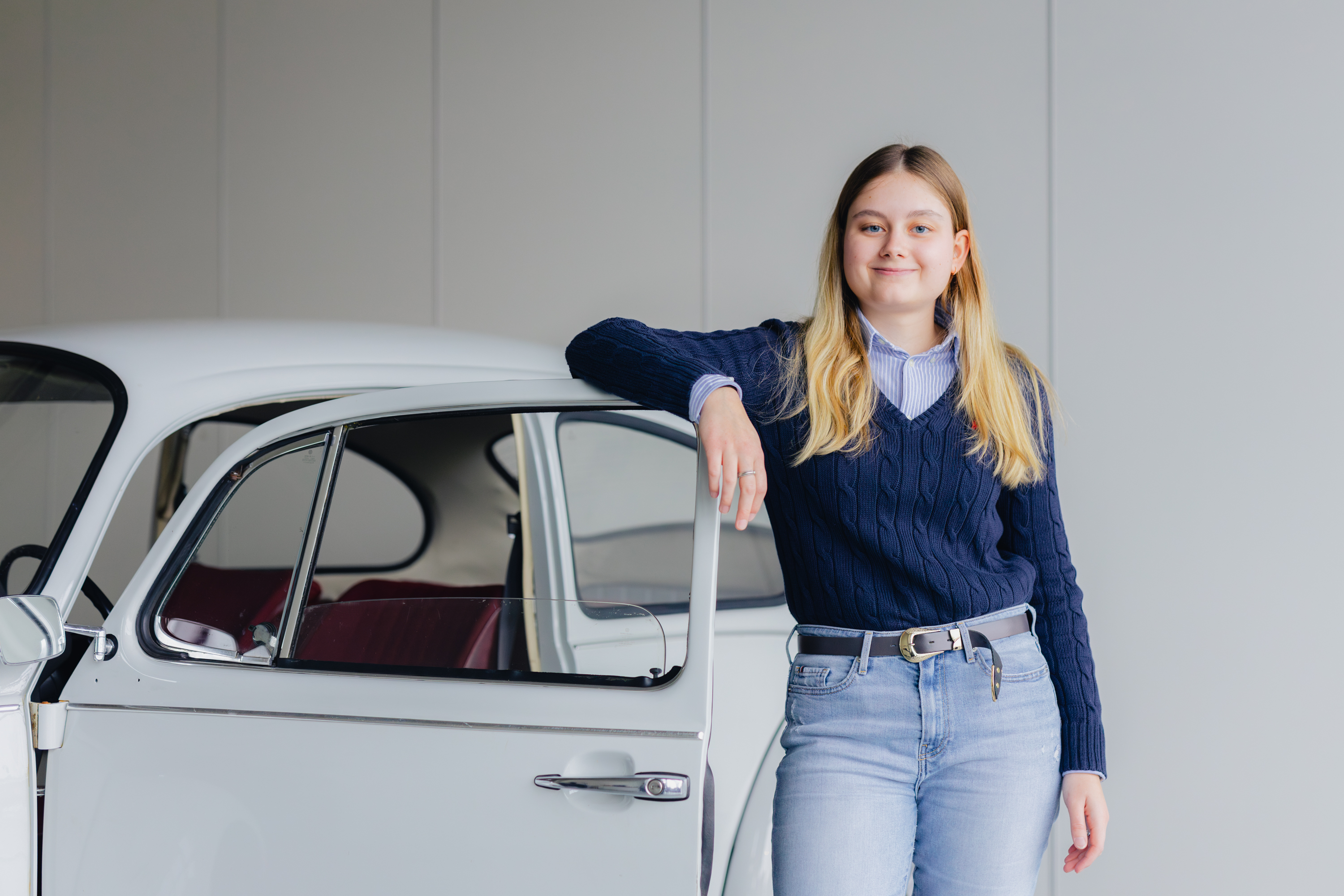 Student leunt ontspannen tegen een klassiek voertuig, symbool voor een positieve studie-omslag