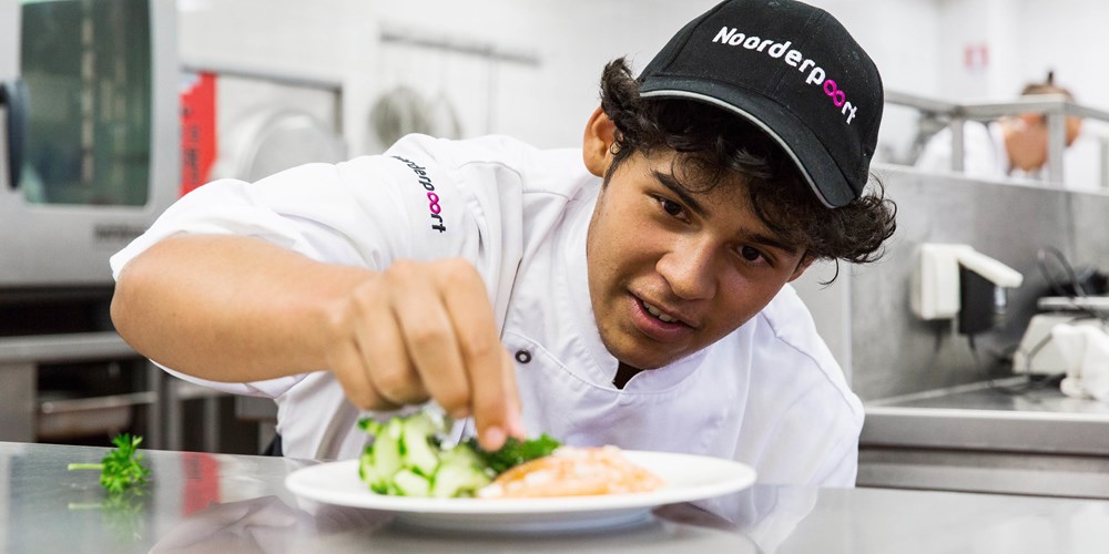 Student bereidt een gerecht in een professionele keuken van een mbo-instelling in Noord-Nederland.
