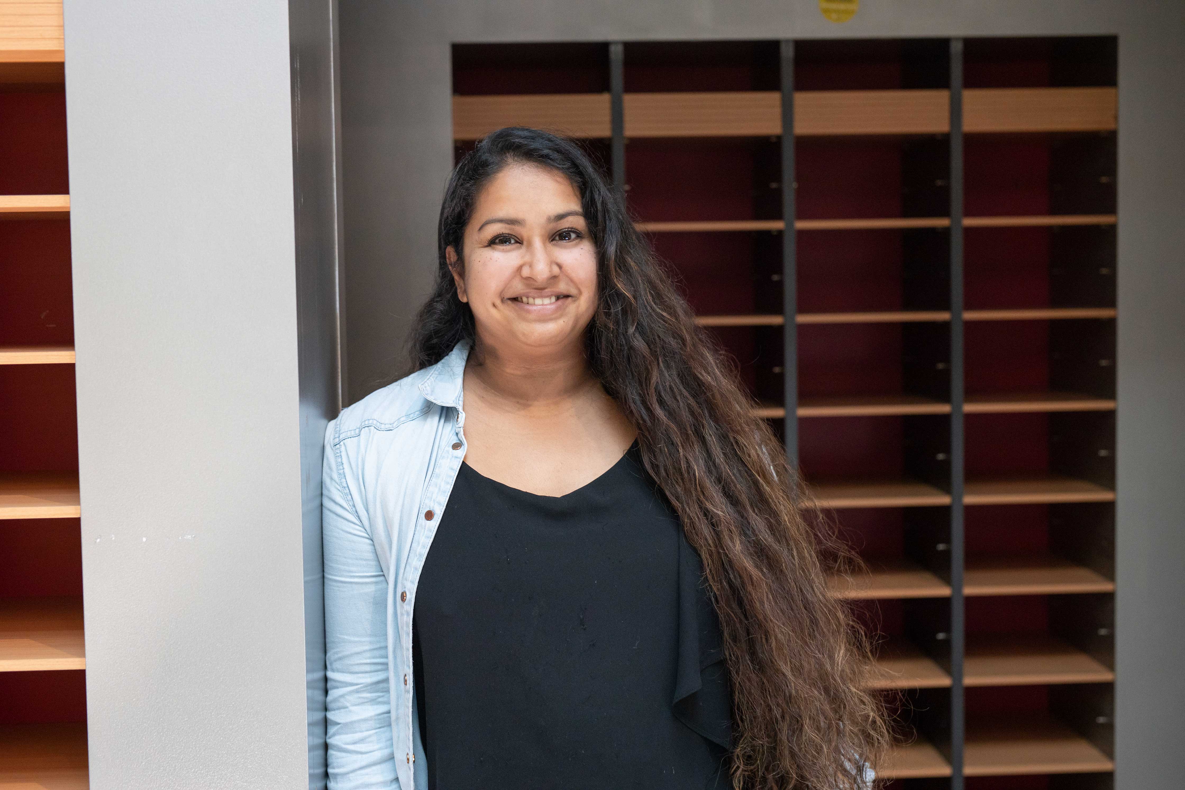 Toekomstige student met ontspannen houding in een onderwijsomgeving met lege vakken achter haar