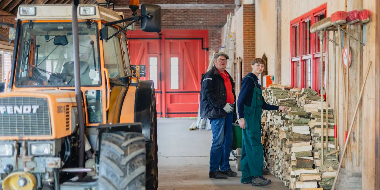 Student en begeleider staan bij gestapeld brandhout in werkruimte tijdens stage bij WerkPro Op Ewsum