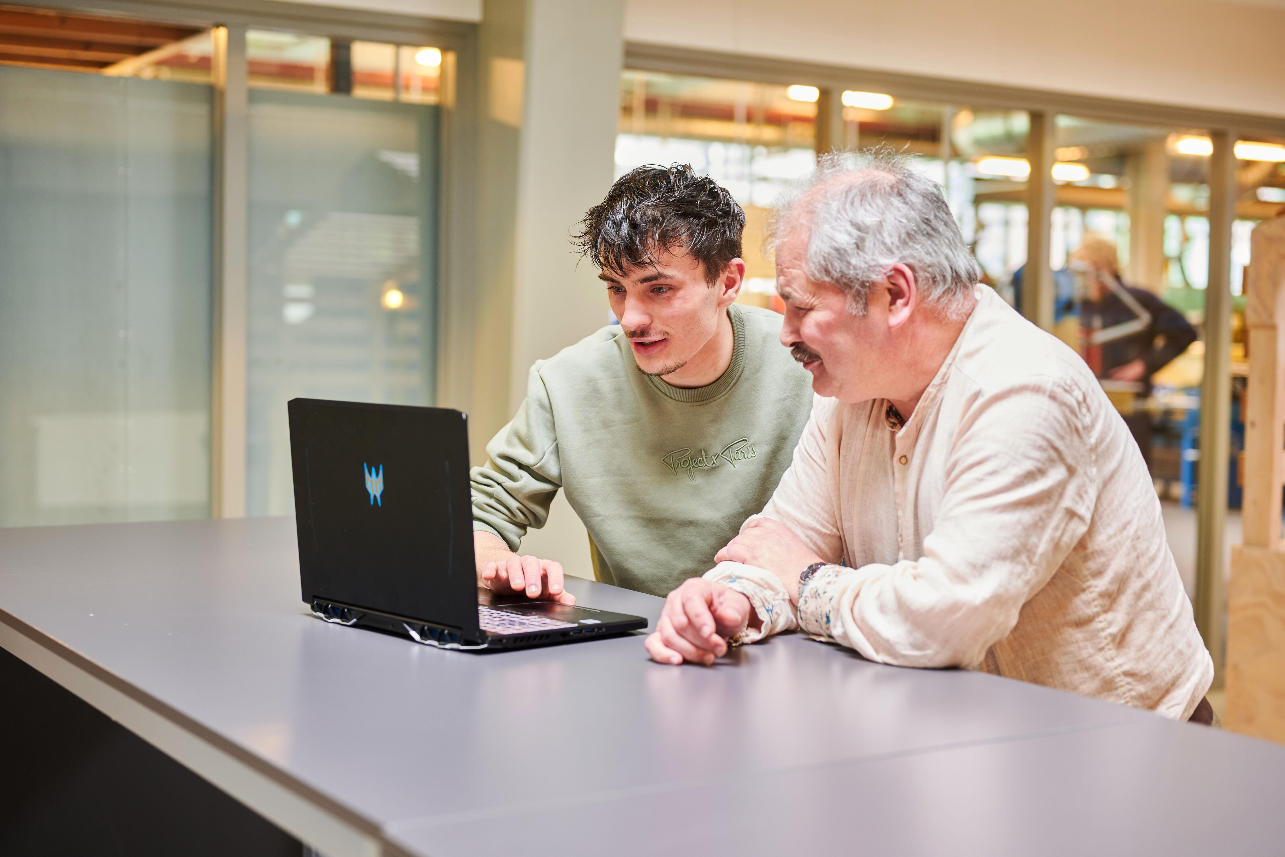 Student en volwassen cursist werken samen aan laptop tijdens een mbo-opleiding voor volwassenen.
