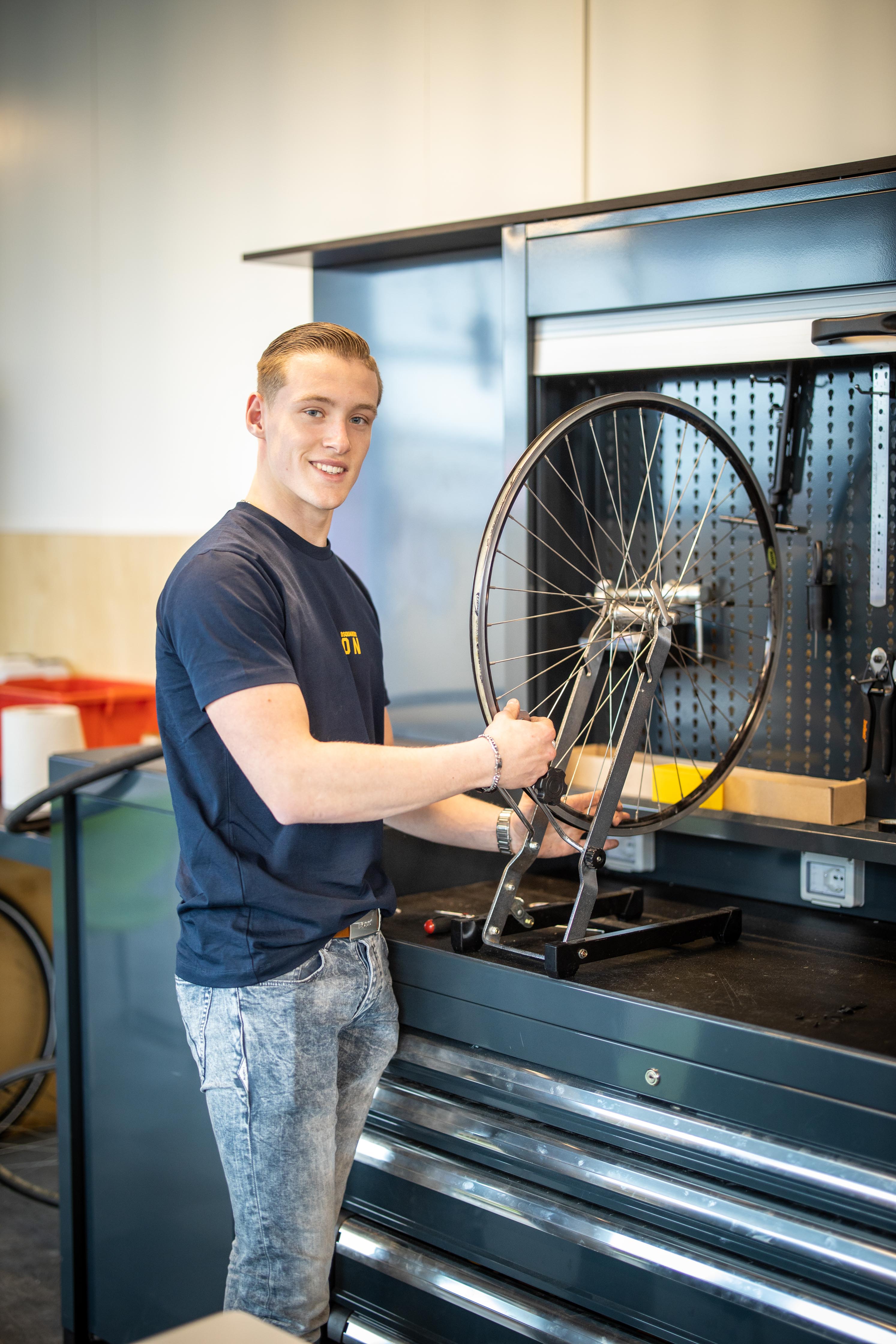 Student oefent met het monteren van een wiel in een werkplaats voor praktijkleren bij Noorderpoort