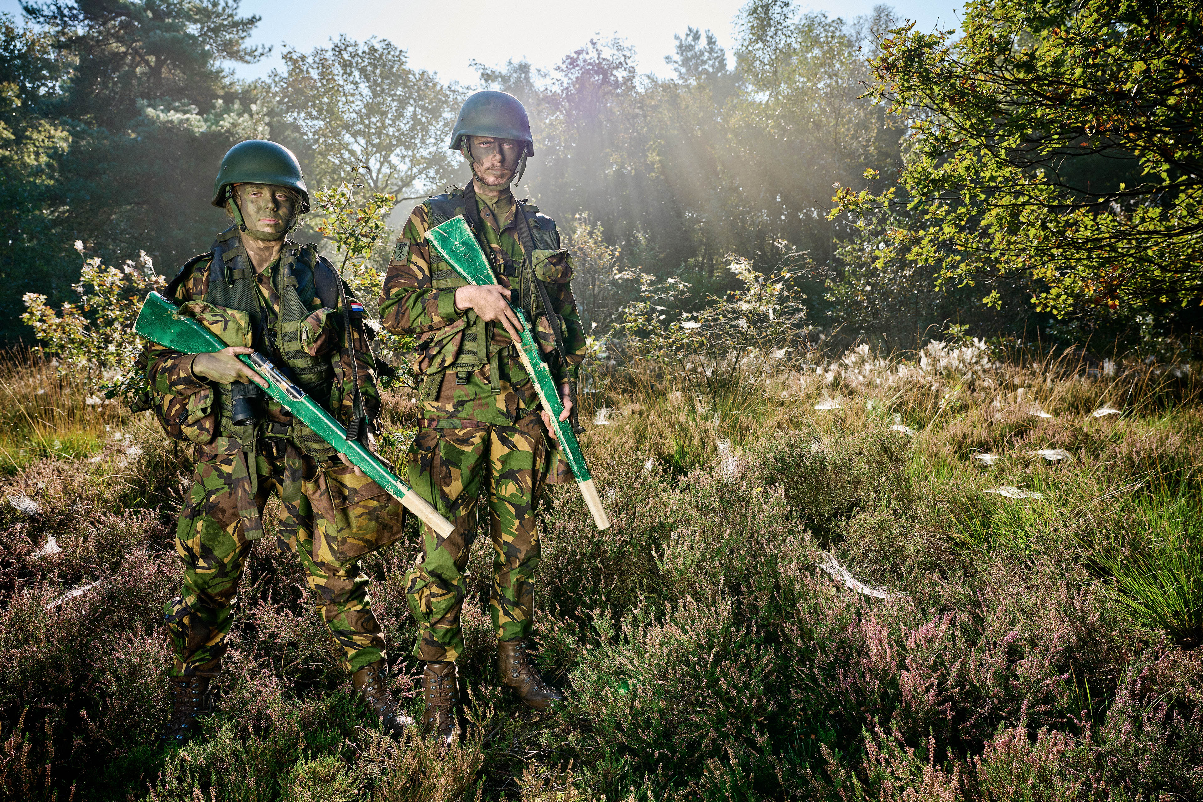 Twee studenten in camouflagekleding tijdens een praktijkoefening in een bosrijke omgeving