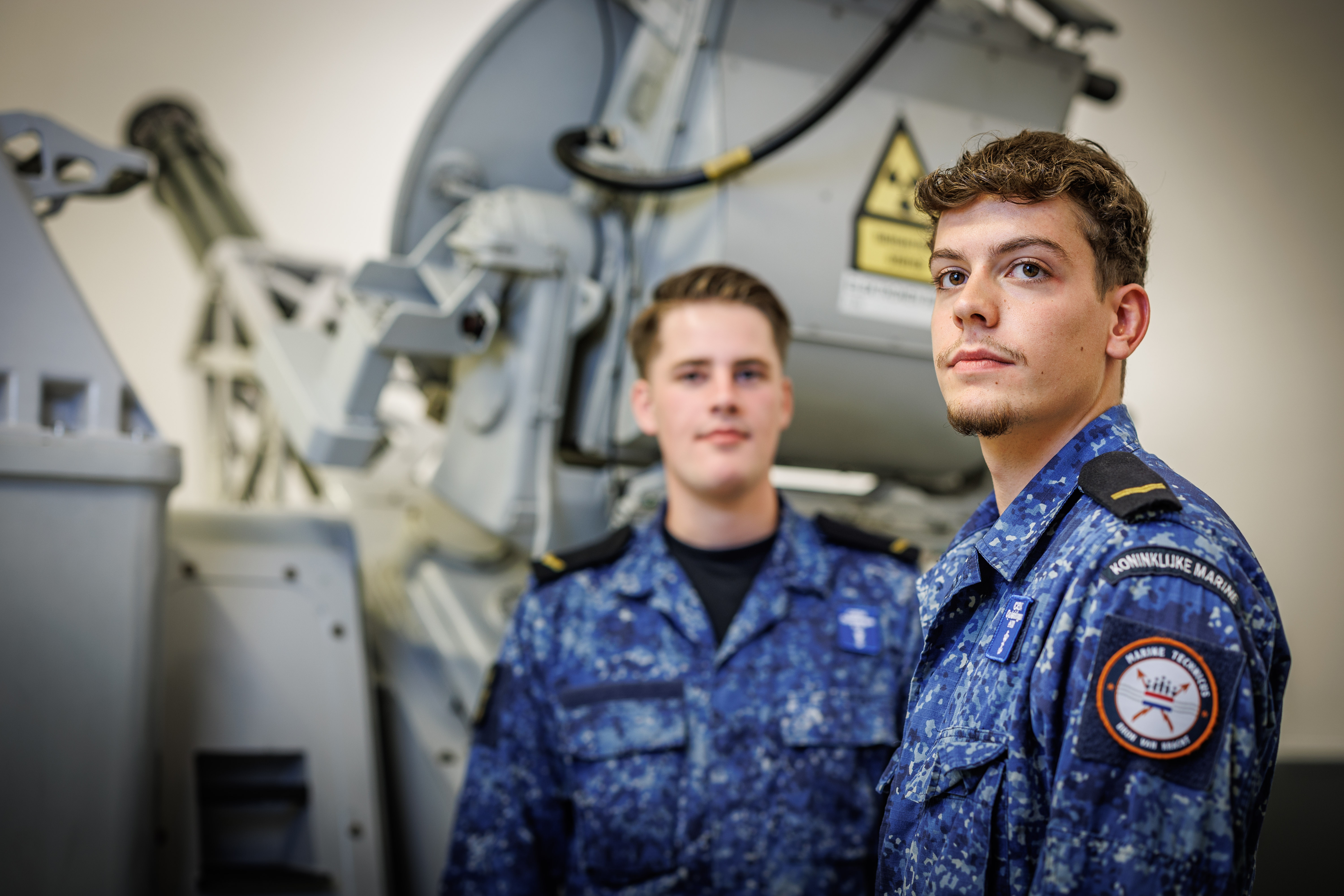 Twee studenten in uniform bij technisch maritiem materieel tijdens praktijkles