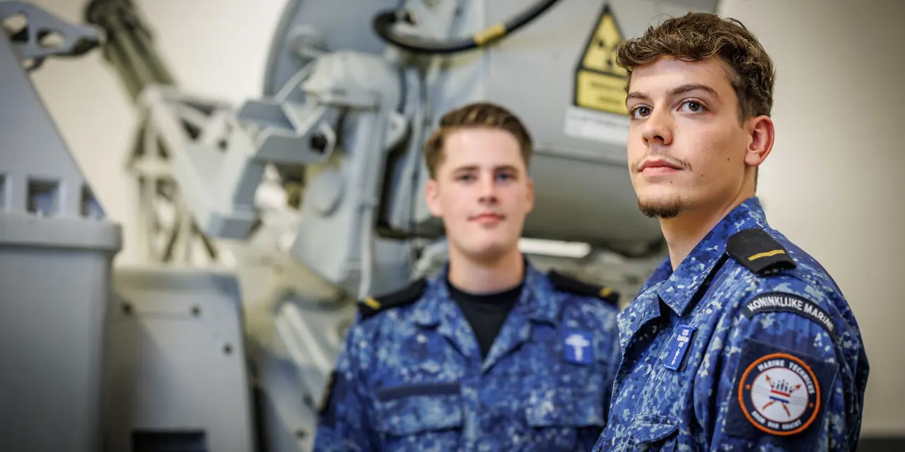 Twee studenten in uniform bij technisch maritiem materieel tijdens praktijkles
