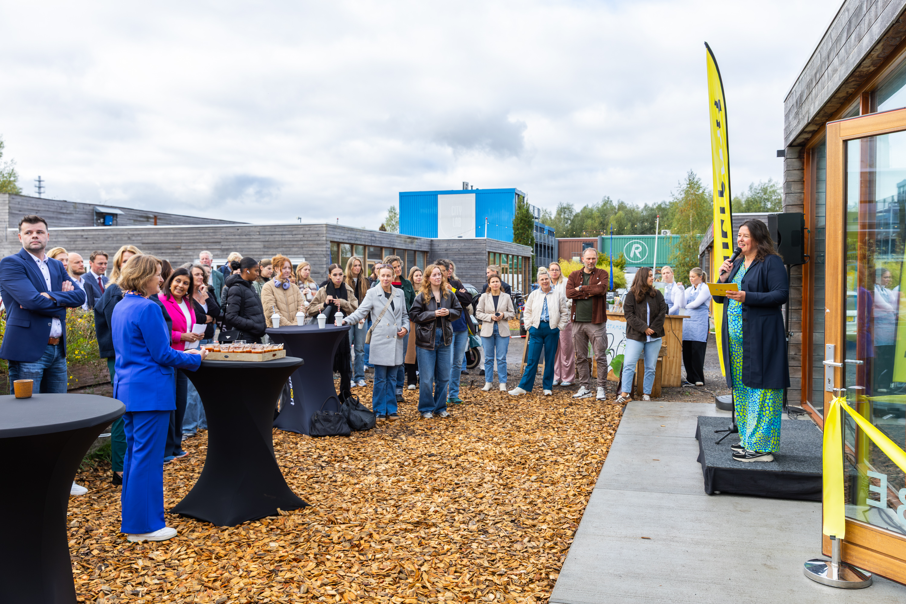 Groep bezoekers luistert naar spreker tijdens opening van nieuwe Route Rubicon-locatie van Noorderpoort in Groningen.