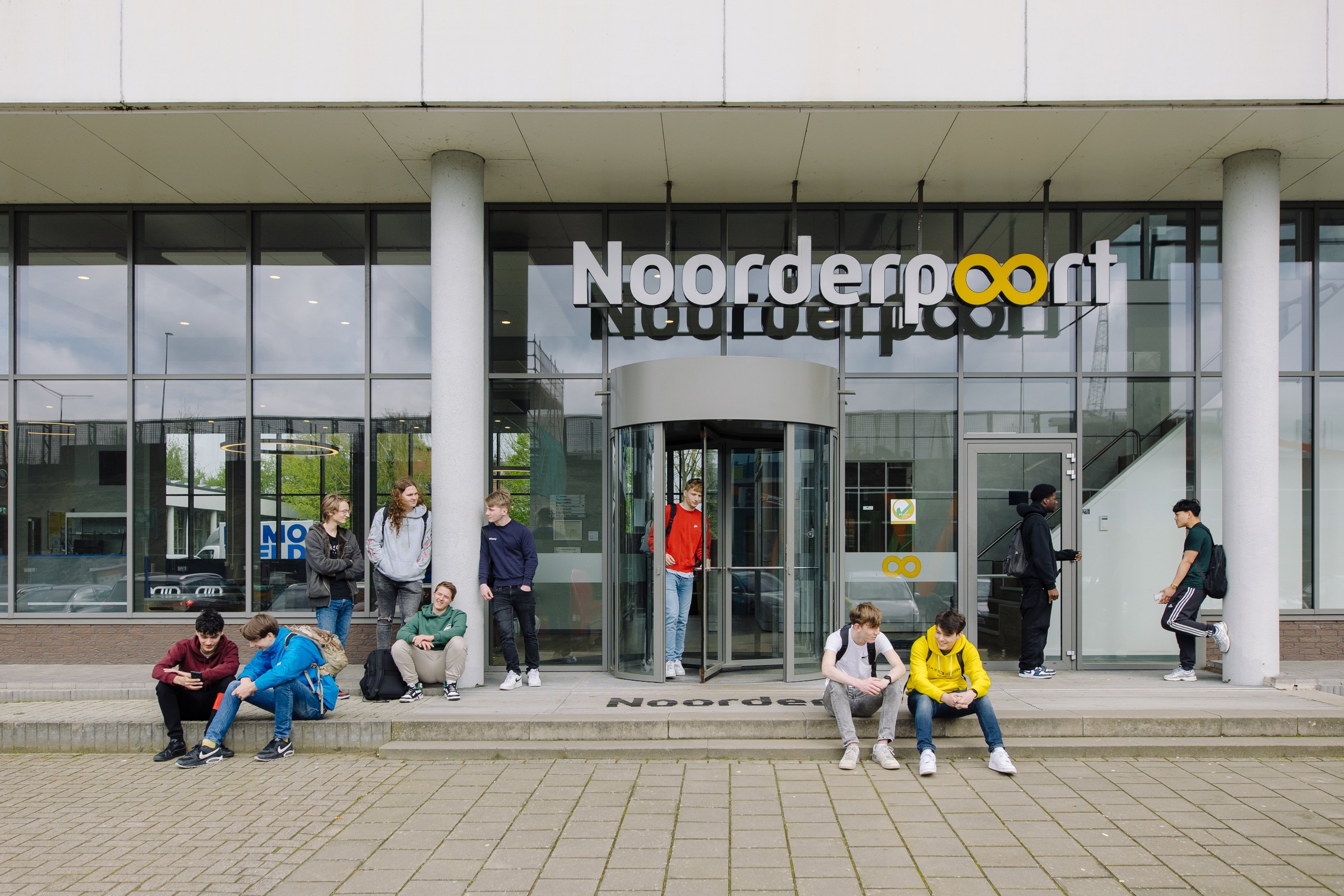 Toekomstige studenten wachten en spreken met elkaar bij de hoofdingang van Noorderpoort onderwijsorganisatie