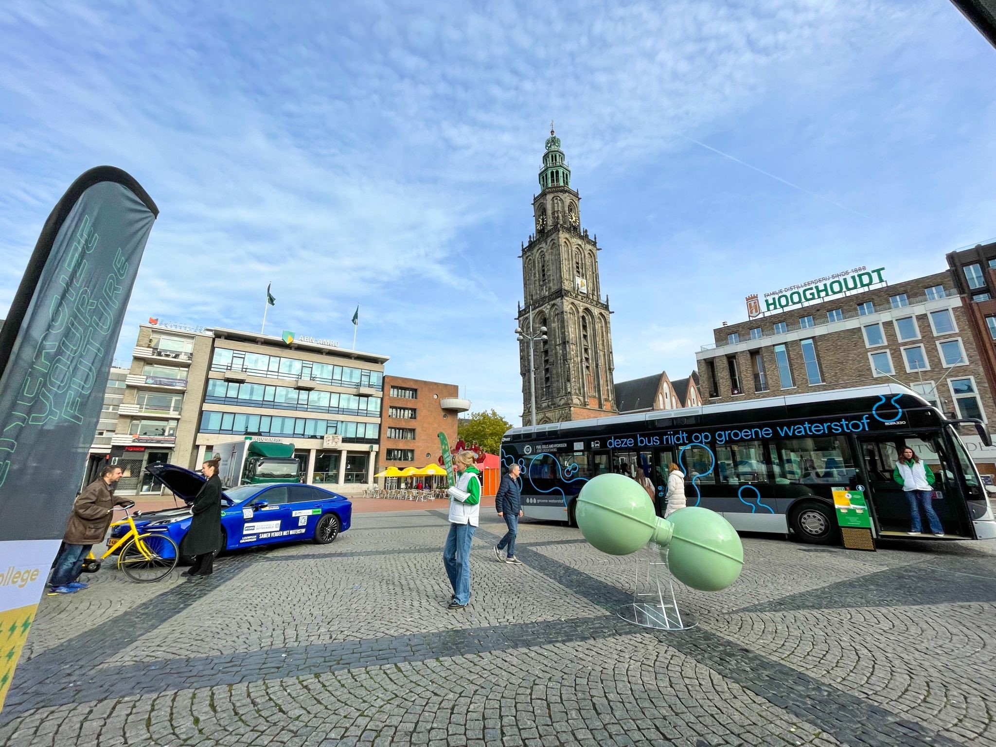 Mensen verkennen innovaties rondom waterstoftechnologie in openbaar plein in Groningen met bus en model centraal