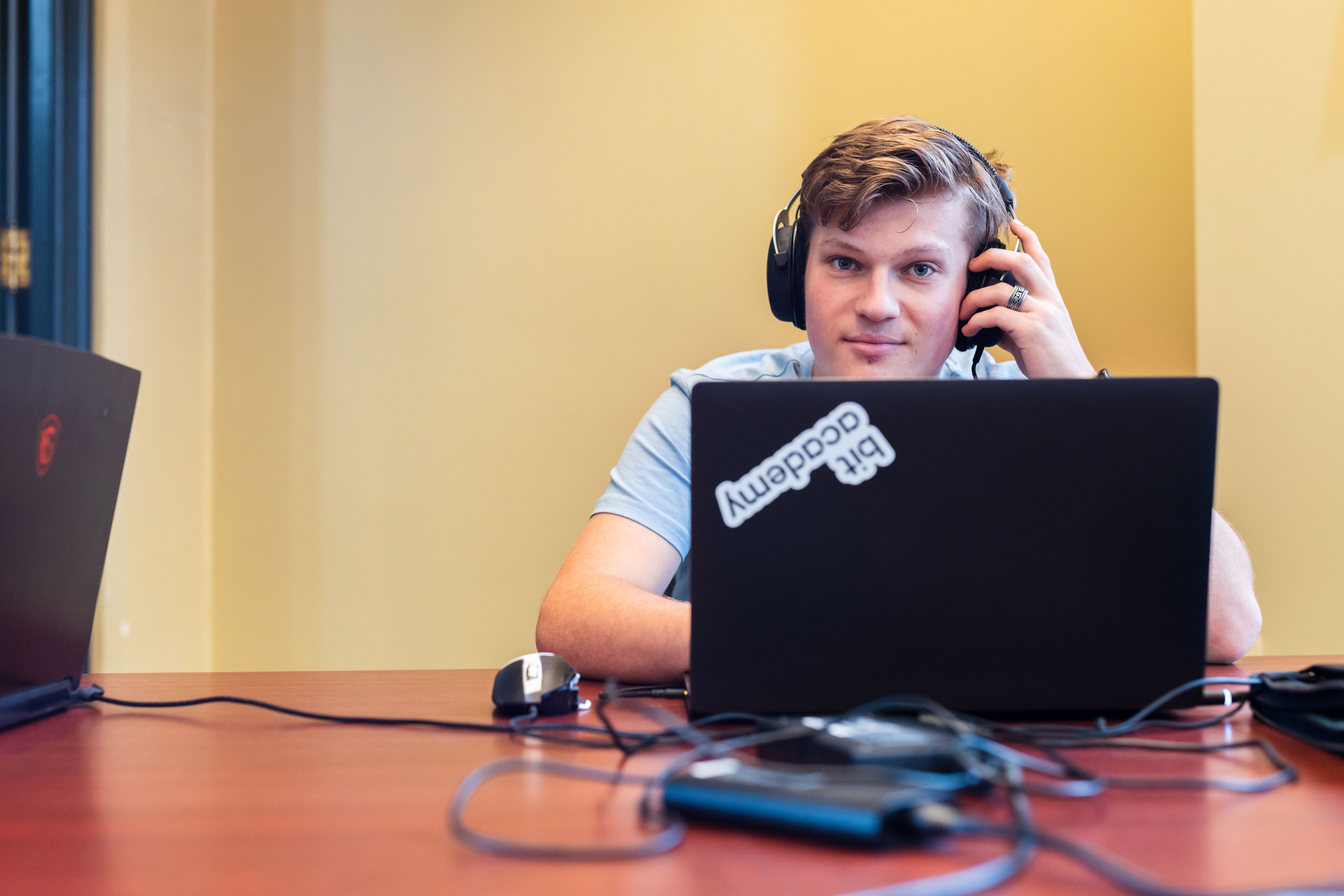 Student werkt geconcentreerd met laptop en koptelefoon, verdiept in IT-ontwikkelingen bij Noorderpoort